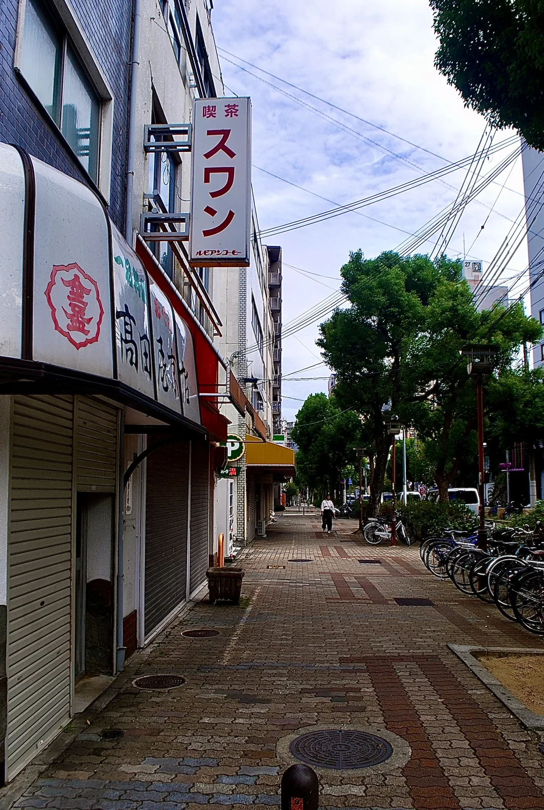 「喫茶 スワン」の縦看板と、並木の続く広い歩道