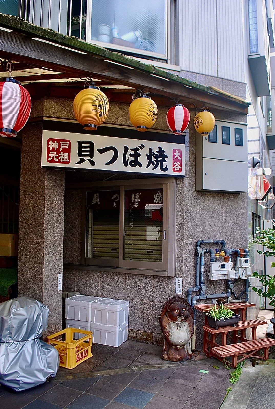 「神戸元祖 貝つぼ焼」の看板と提灯、たぬきの置物
