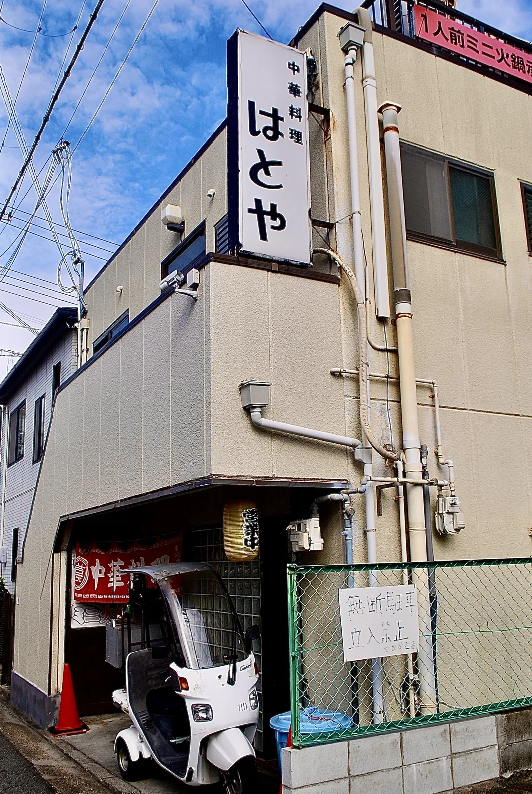 白い縦看板の「中華料理 はとや」と、赤いのれんの店