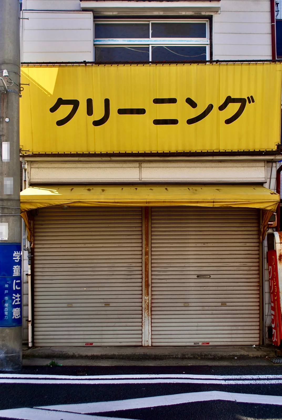 黄色い看板と下ろされたシャッターの店先