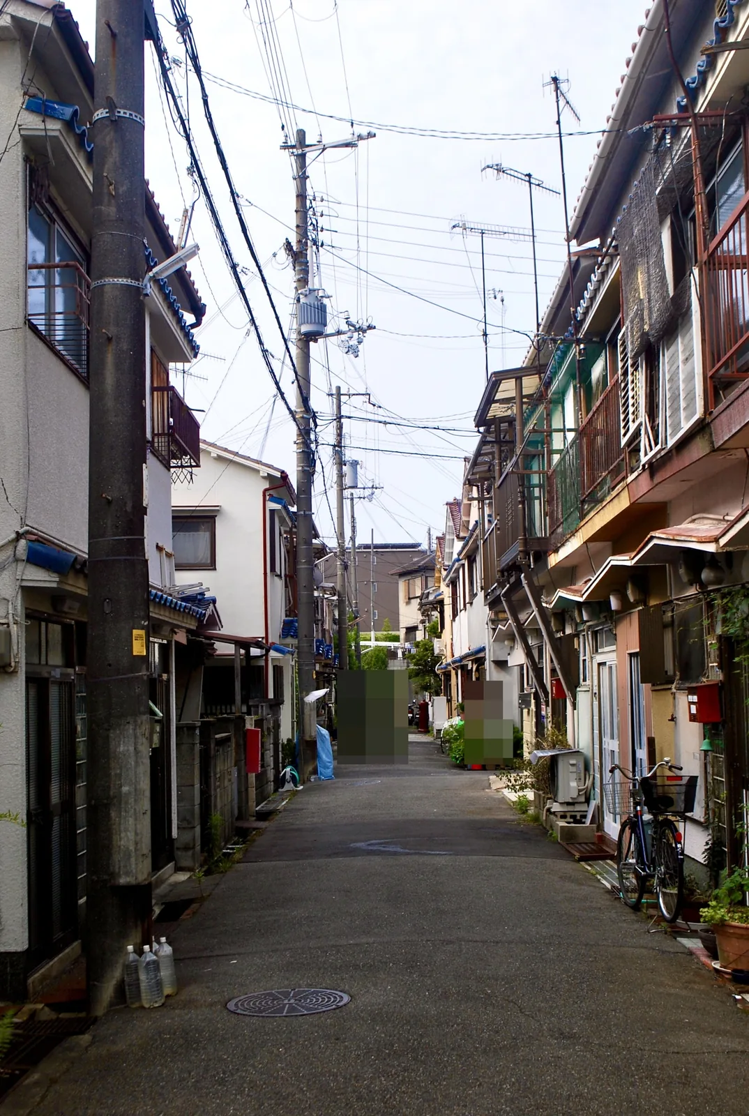 長屋と自転車、植木鉢が並ぶ、まっすぐな細い路地
