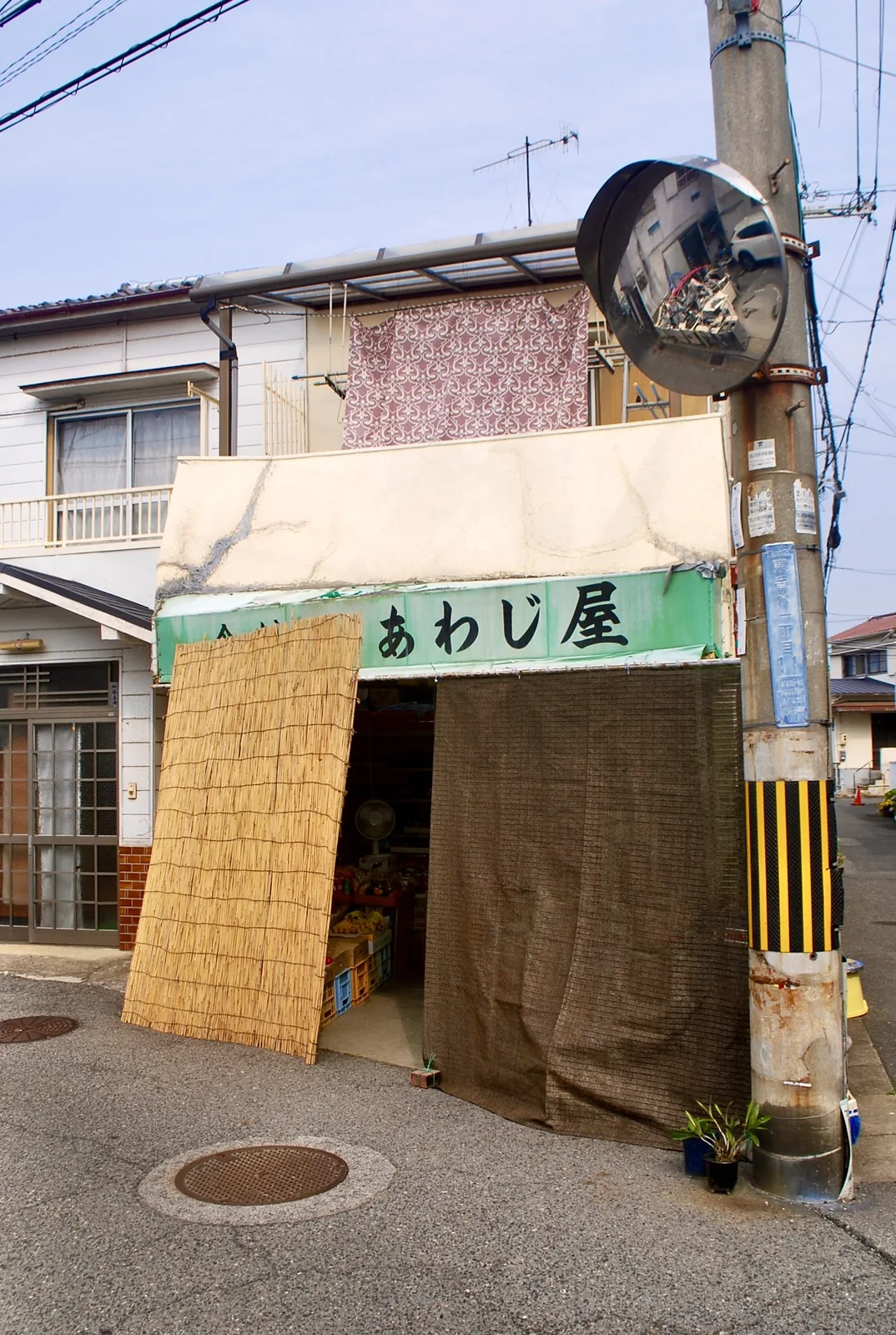 すだれと日よけの布がかかる、角の八百屋「あわじ屋」