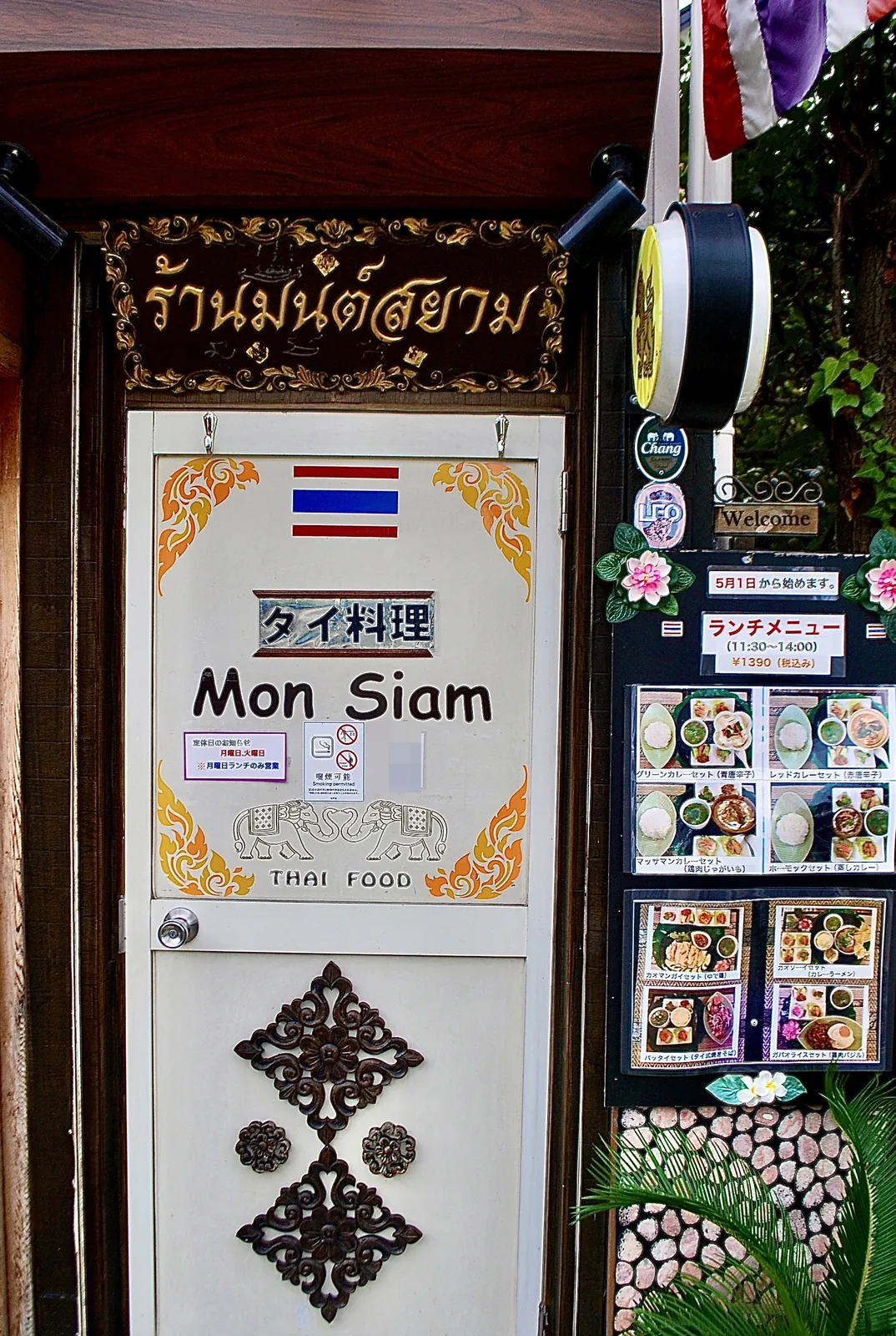 金色の飾り看板と、象の絵が描かれた白い扉のタイ料理店
