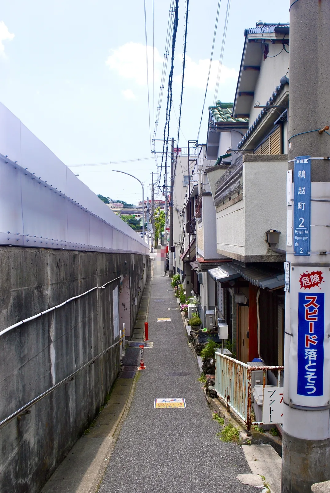 町名表示のある電柱と、高い壁と家々に挟まれた細い路地