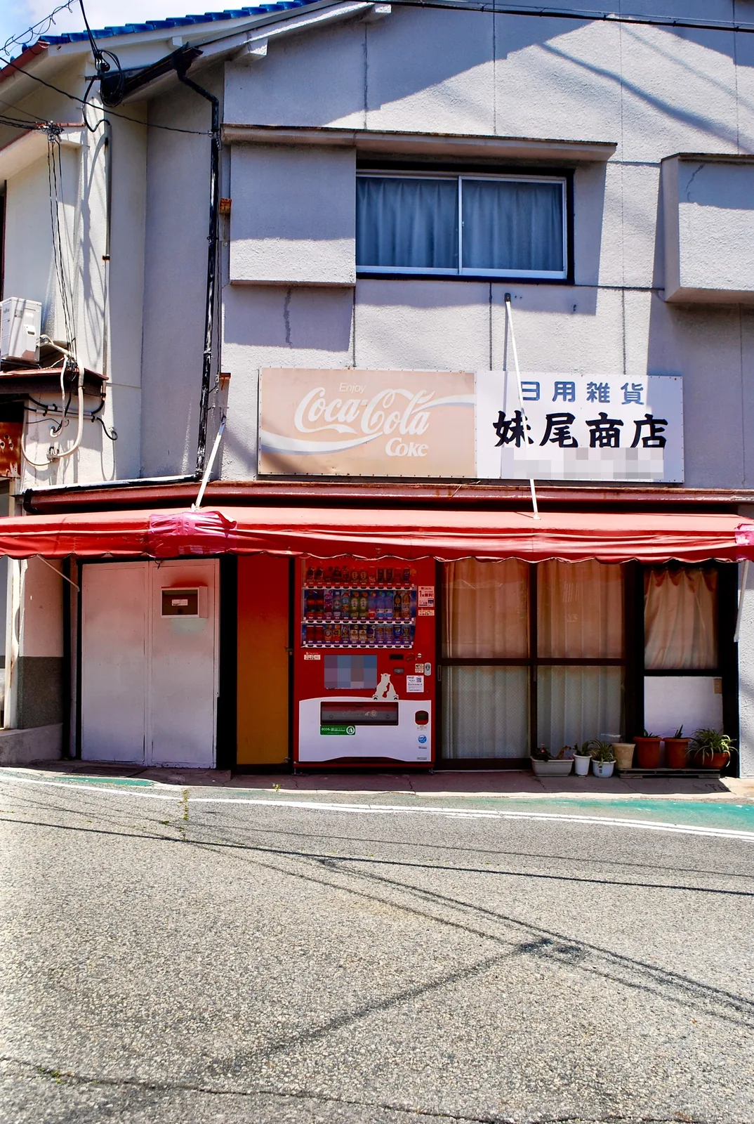 赤い日よけと古いコカ・コーラの看板のある、昔ながらの商店