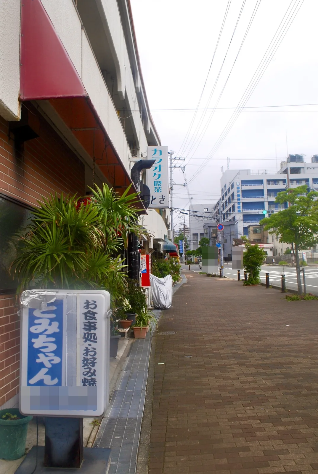 お食事処・お好み焼の立て看板と、レンガの歩道が続く通り