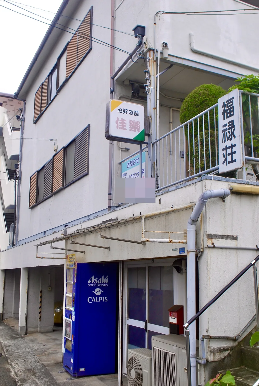 「福禄荘」の看板と、青い自動販売機のある古いアパート