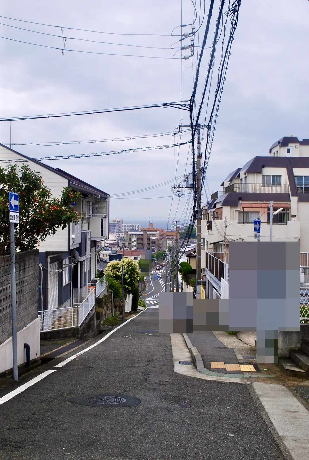 坂の上から、カーブを描いて街並みと海へ下っていく道
