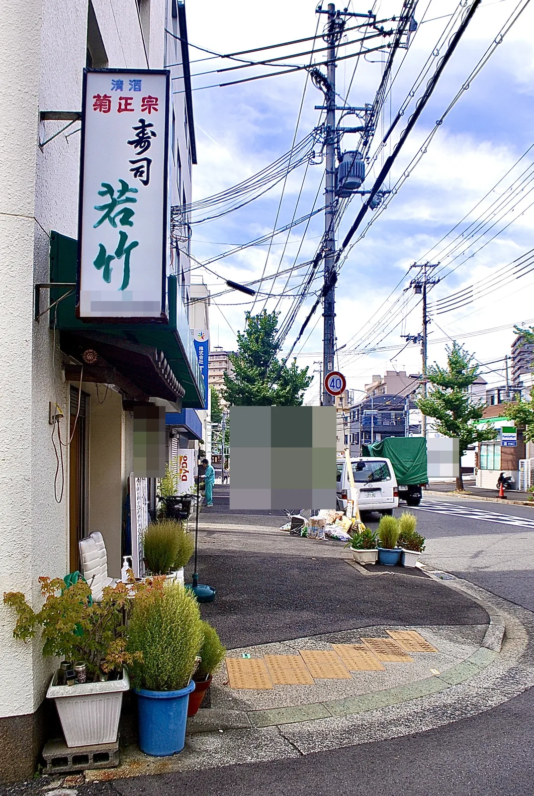 「寿司 若竹」の縦看板と、植木の並ぶ交差点の角