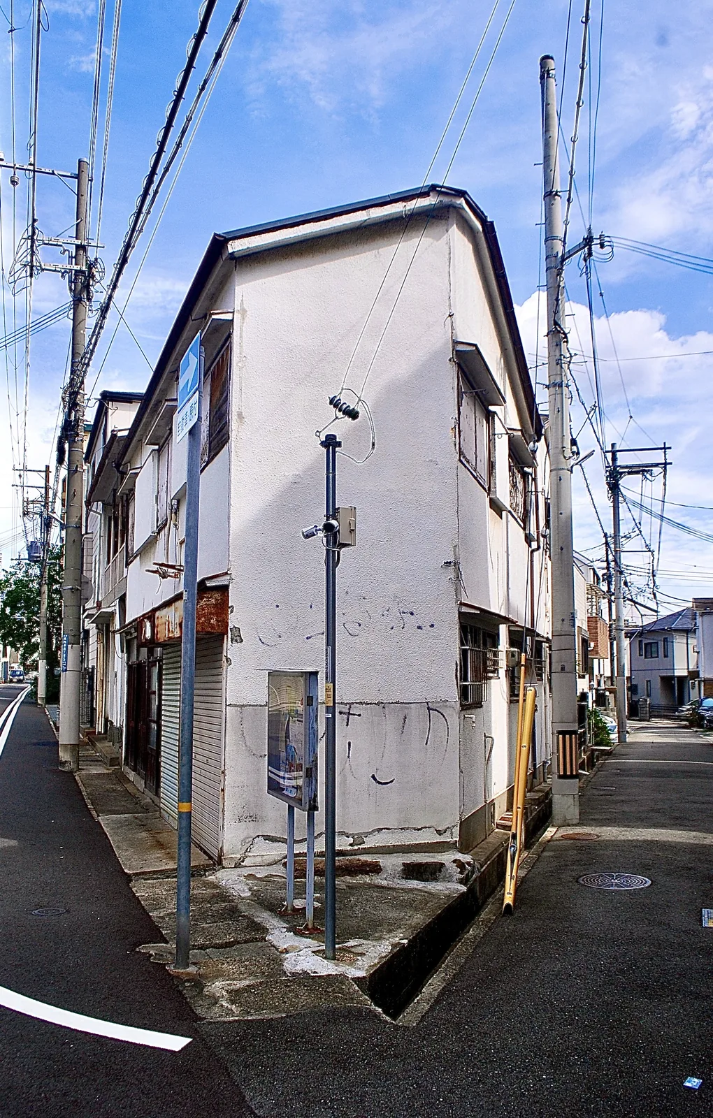 二つの道の分かれ目に立つ、古い木造の家