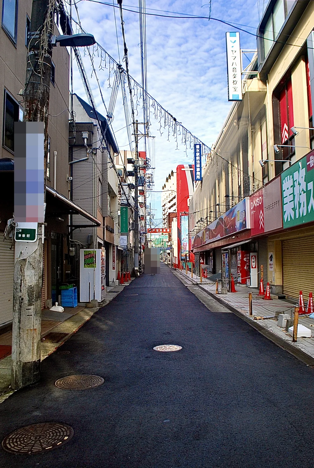 大きな看板と飾りの並ぶ店が両側に続く、駅前のにぎやかな通り