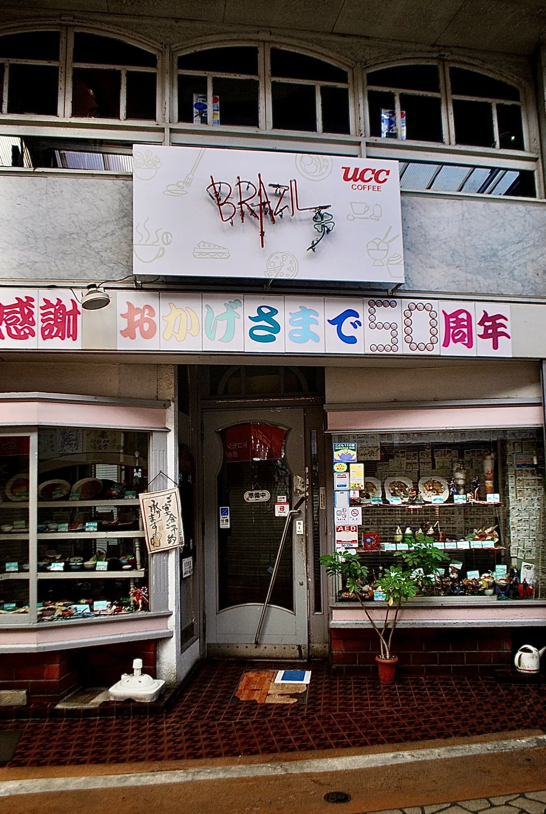 「おかげさまで50周年」の文字と、食品サンプルのショーケースが並ぶ店先