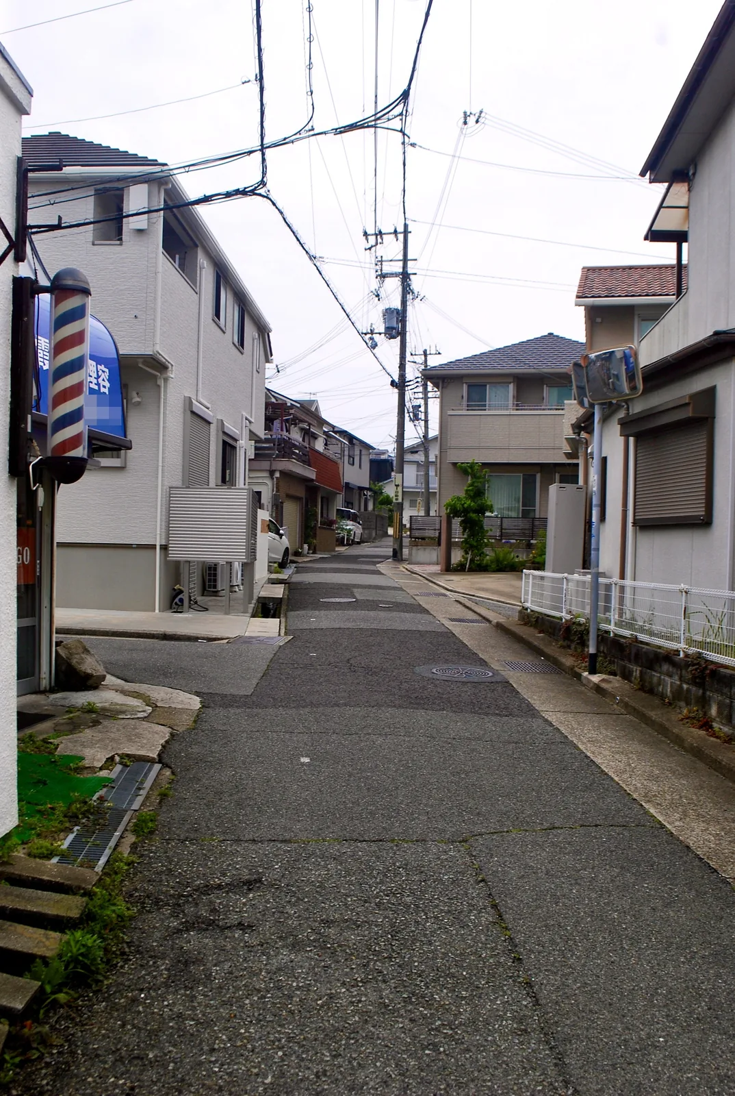 赤白青のサインポールの先に、カーブして上る坂道