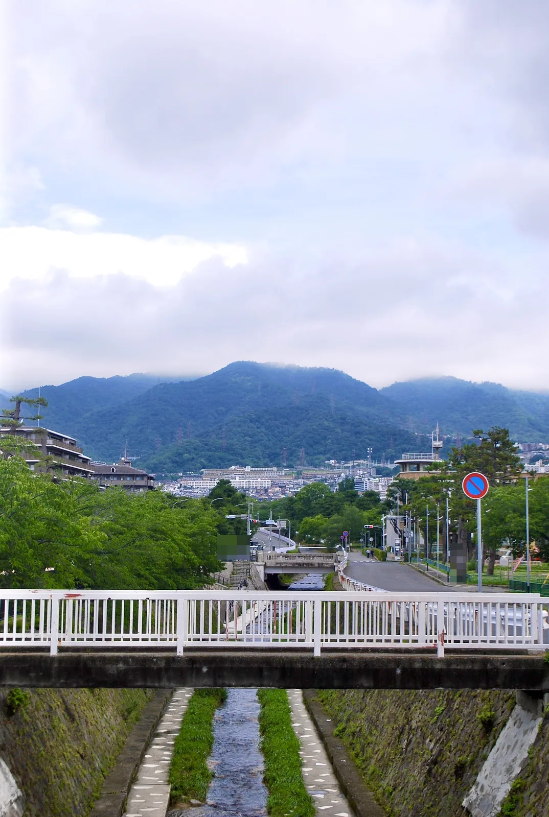 白い欄干の橋の上から、川と六甲山の山並みを望む風景