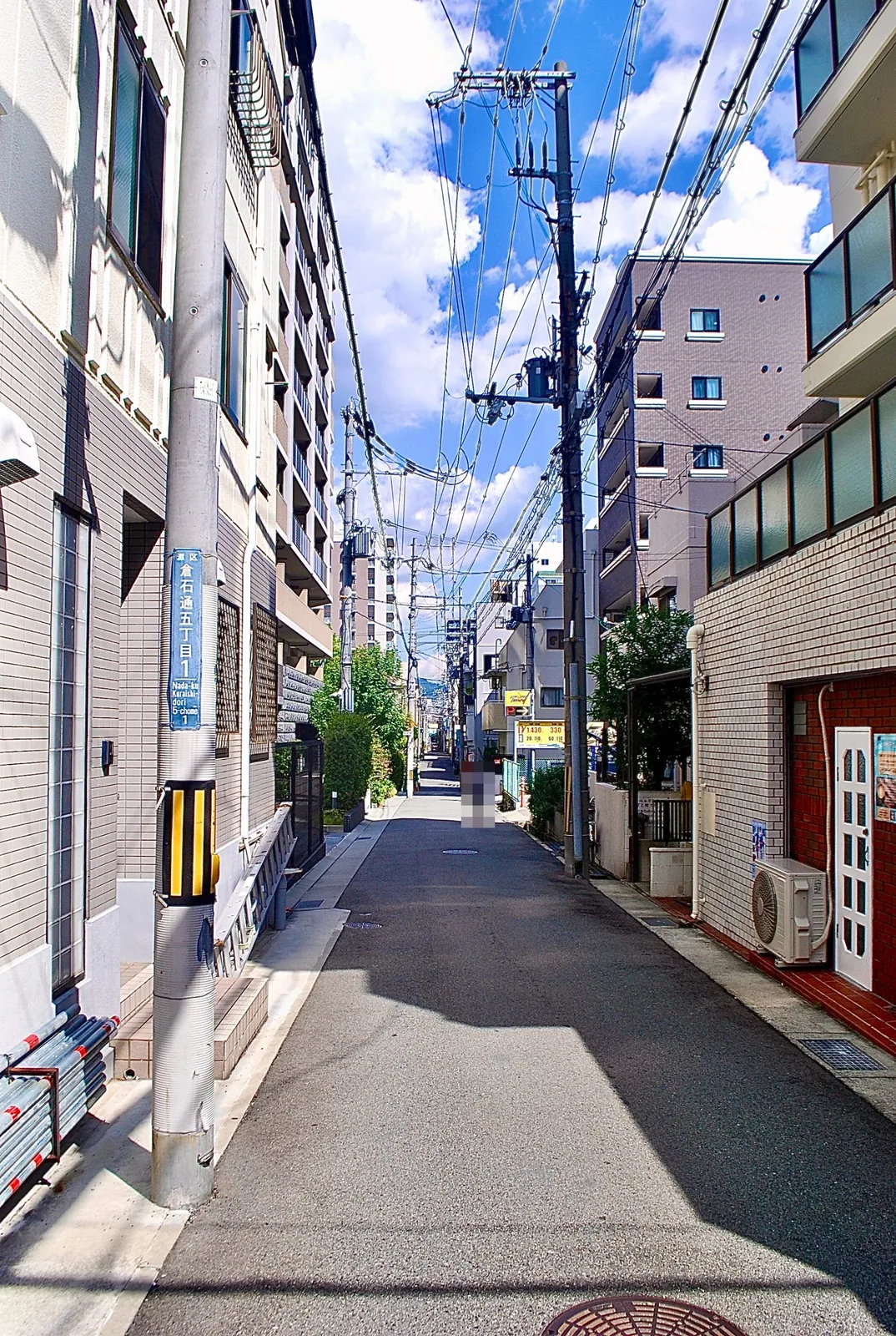 電柱と電線が奥まで続く、雲の浮かぶ青空の下の通り