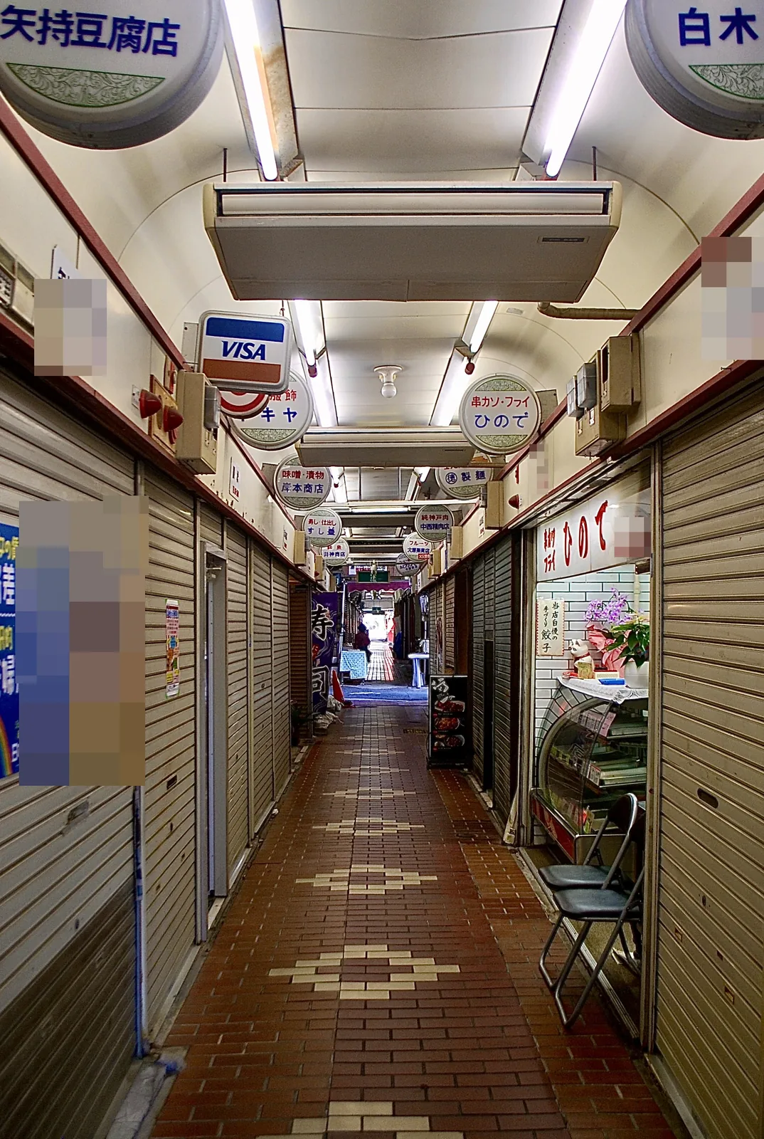 丸い看板が並び、タイルの床がまっすぐ続く市場のアーケード