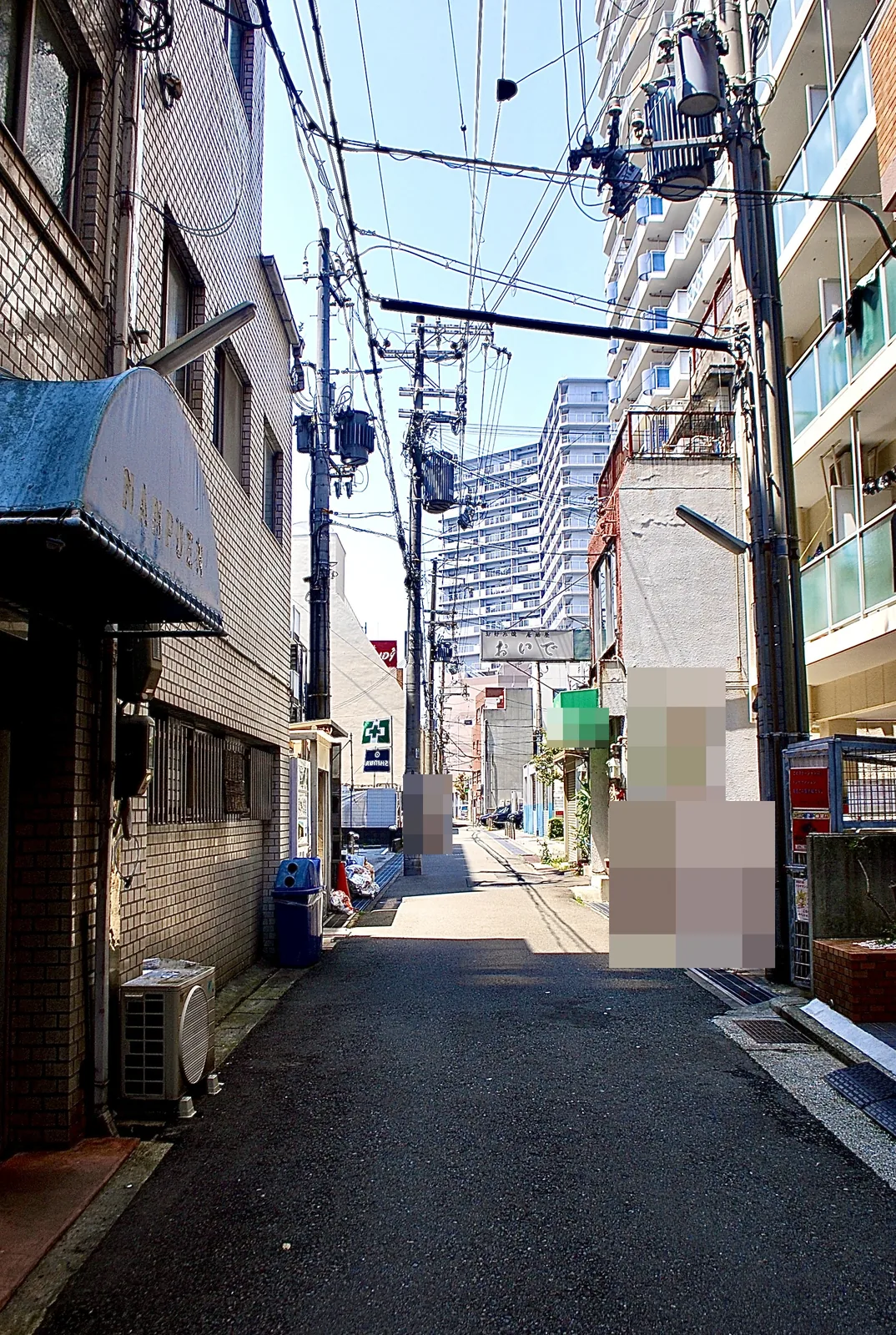 「世界長」の看板や居酒屋の看板が並ぶ、奥へ続く細い道