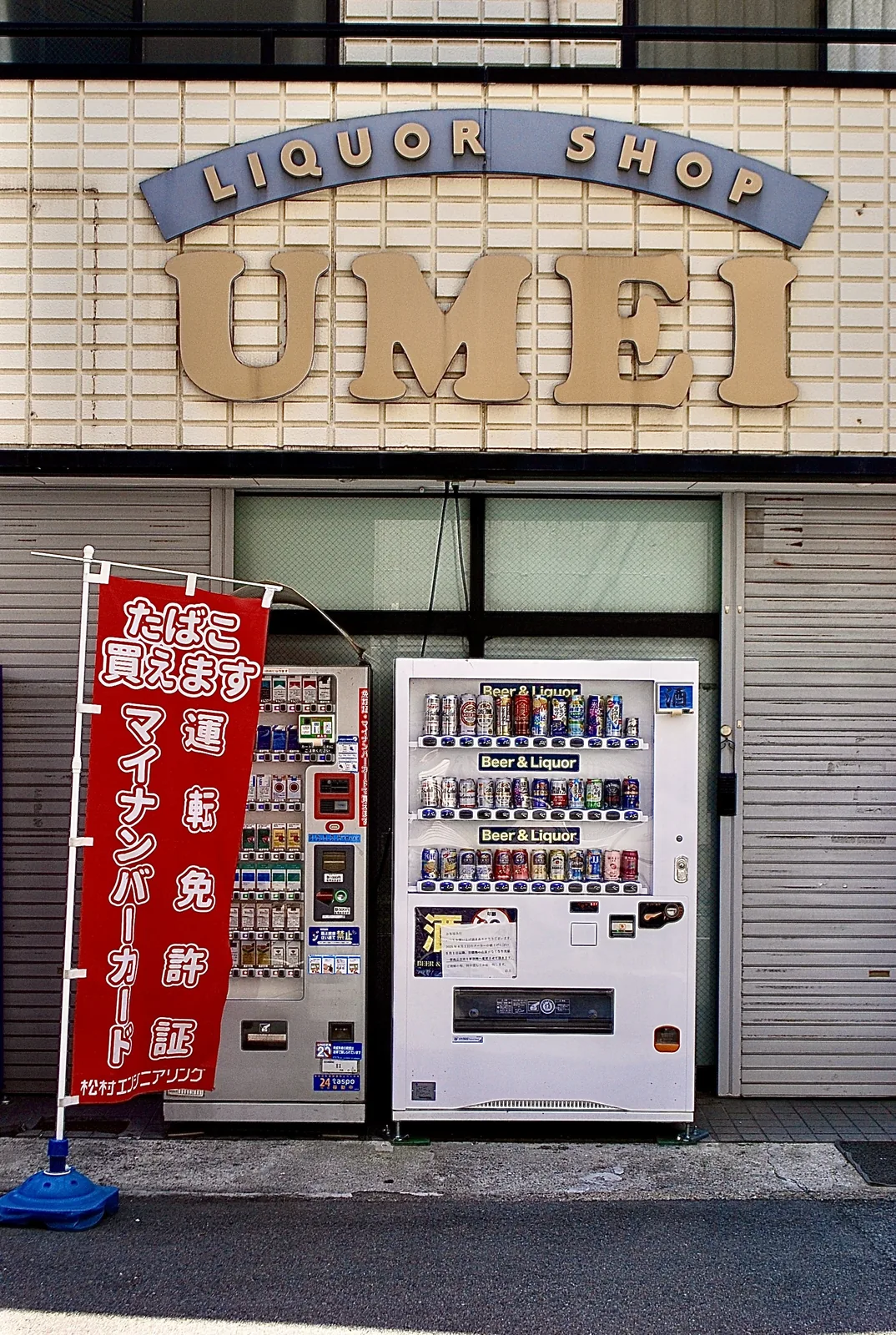 アーチ型の看板と、たばこ・お酒の自動販売機が並ぶ酒店