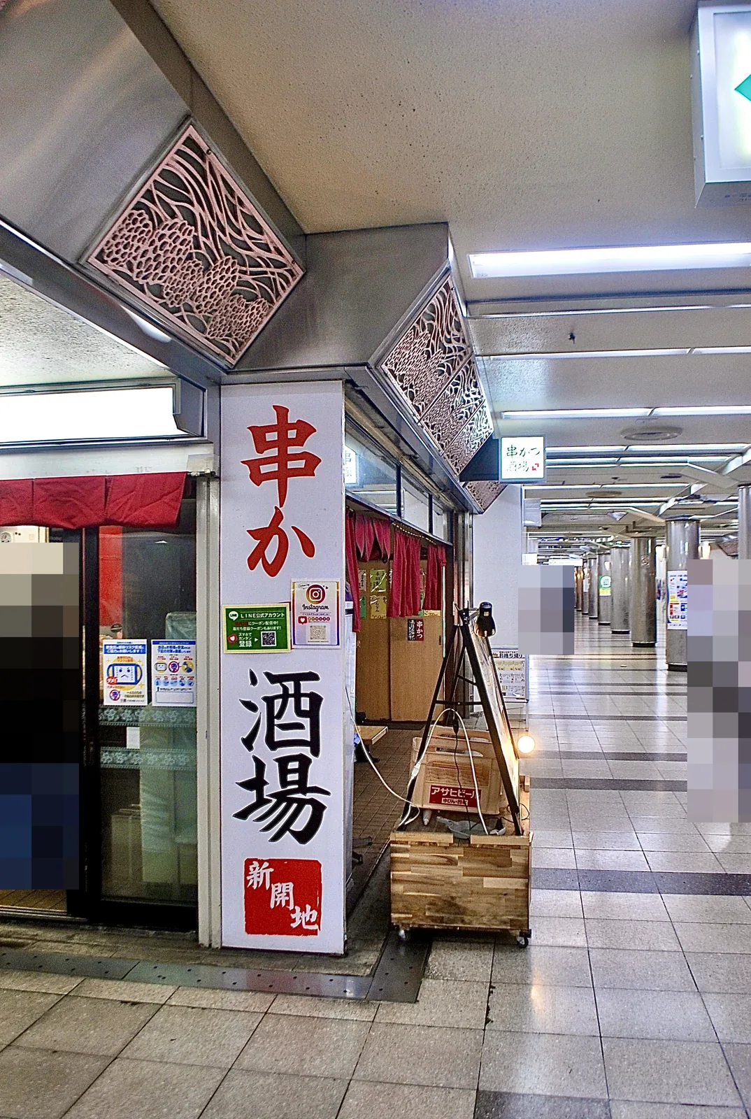 「串かつ 酒場」の看板と、まっすぐ続く地下街