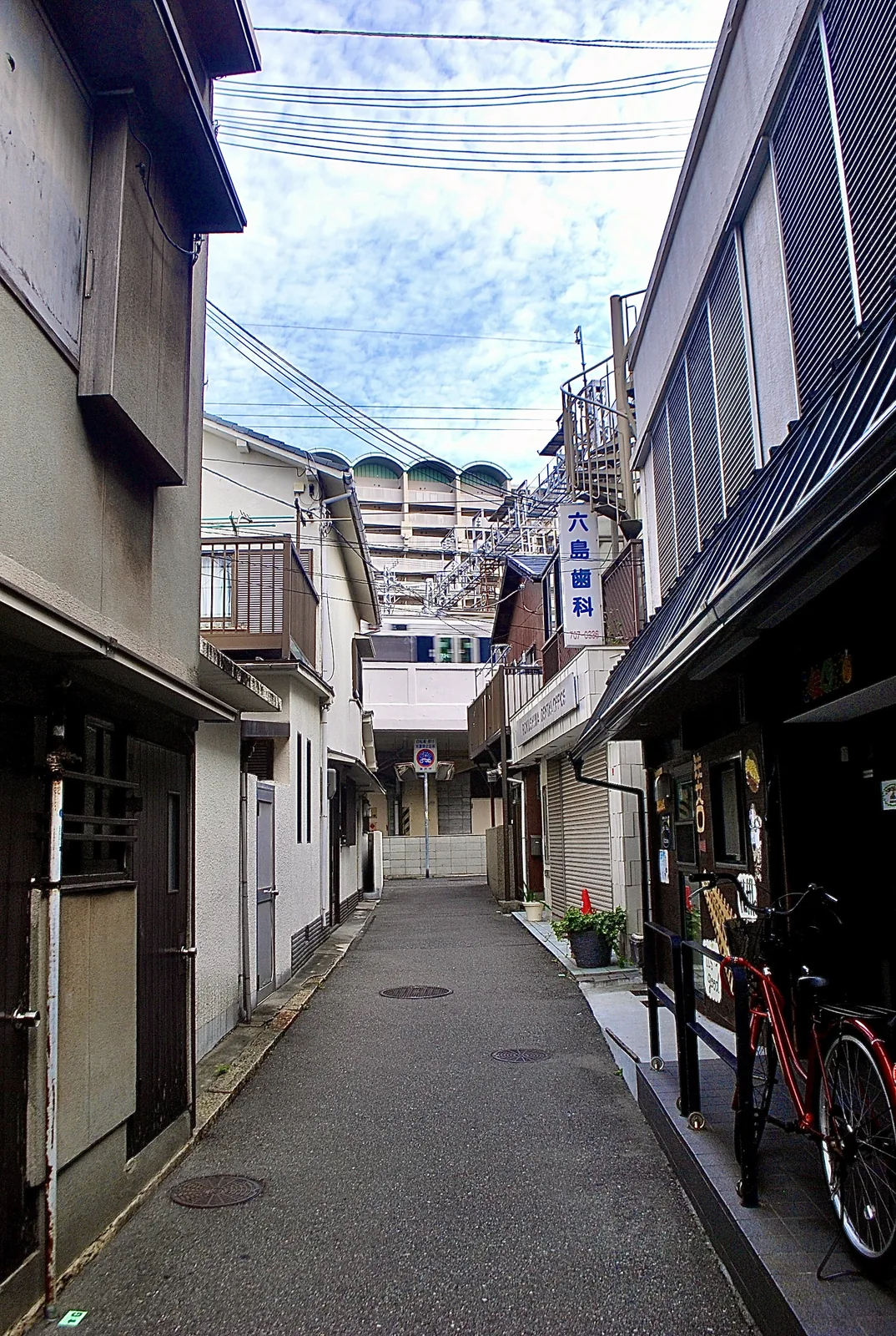 自転車が止まる、看板の下がった細い路地