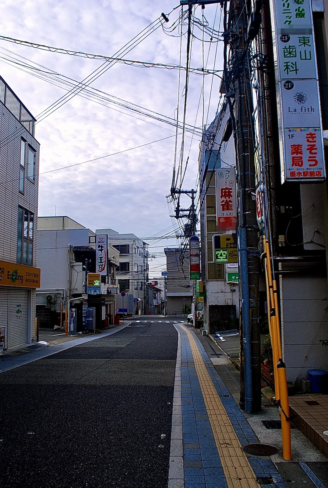 縦長の看板が電柱に寄り添うように並ぶ、駅前の通り