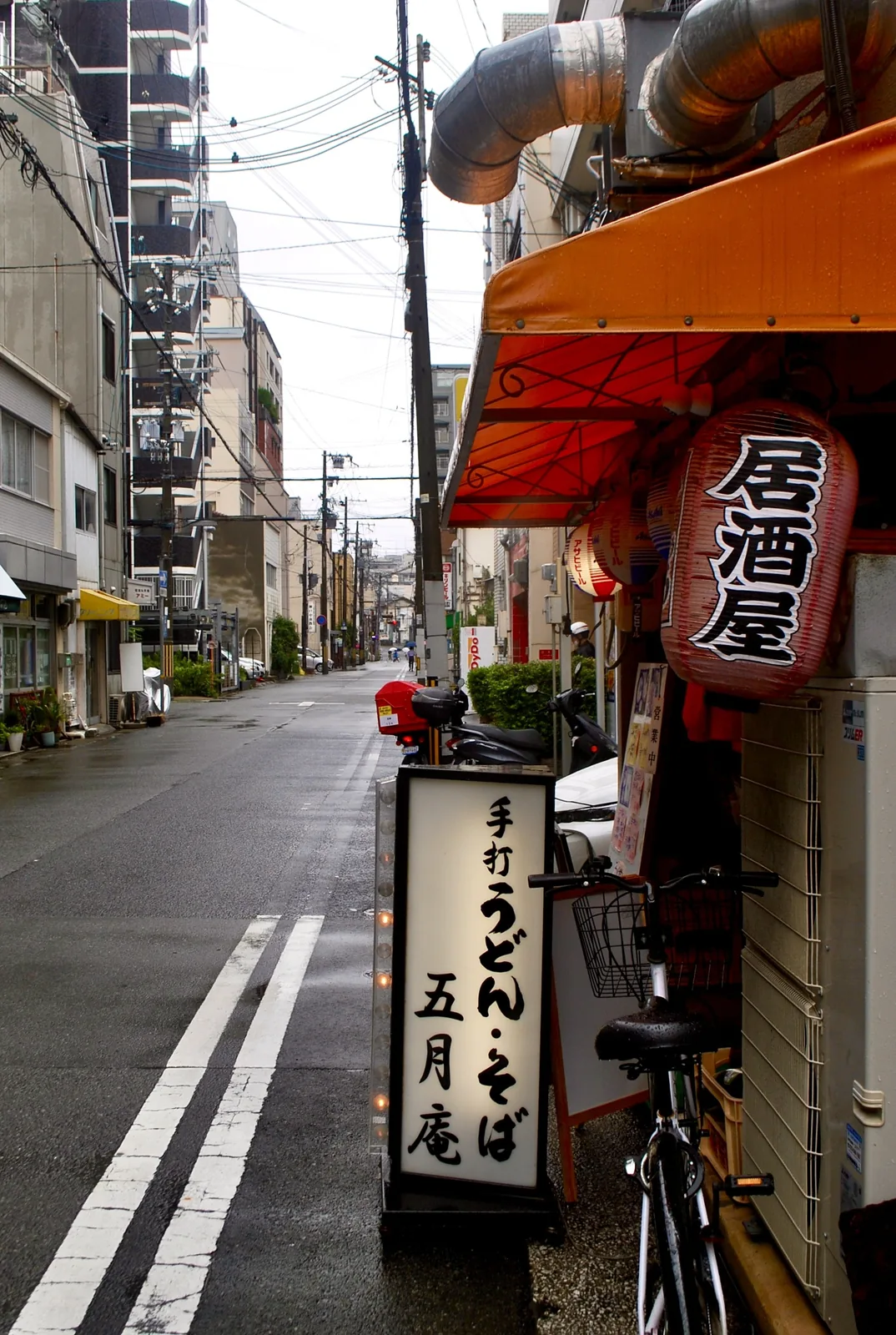 「居酒屋」と書かれた大きな赤提灯と、手打ちうどんの看板