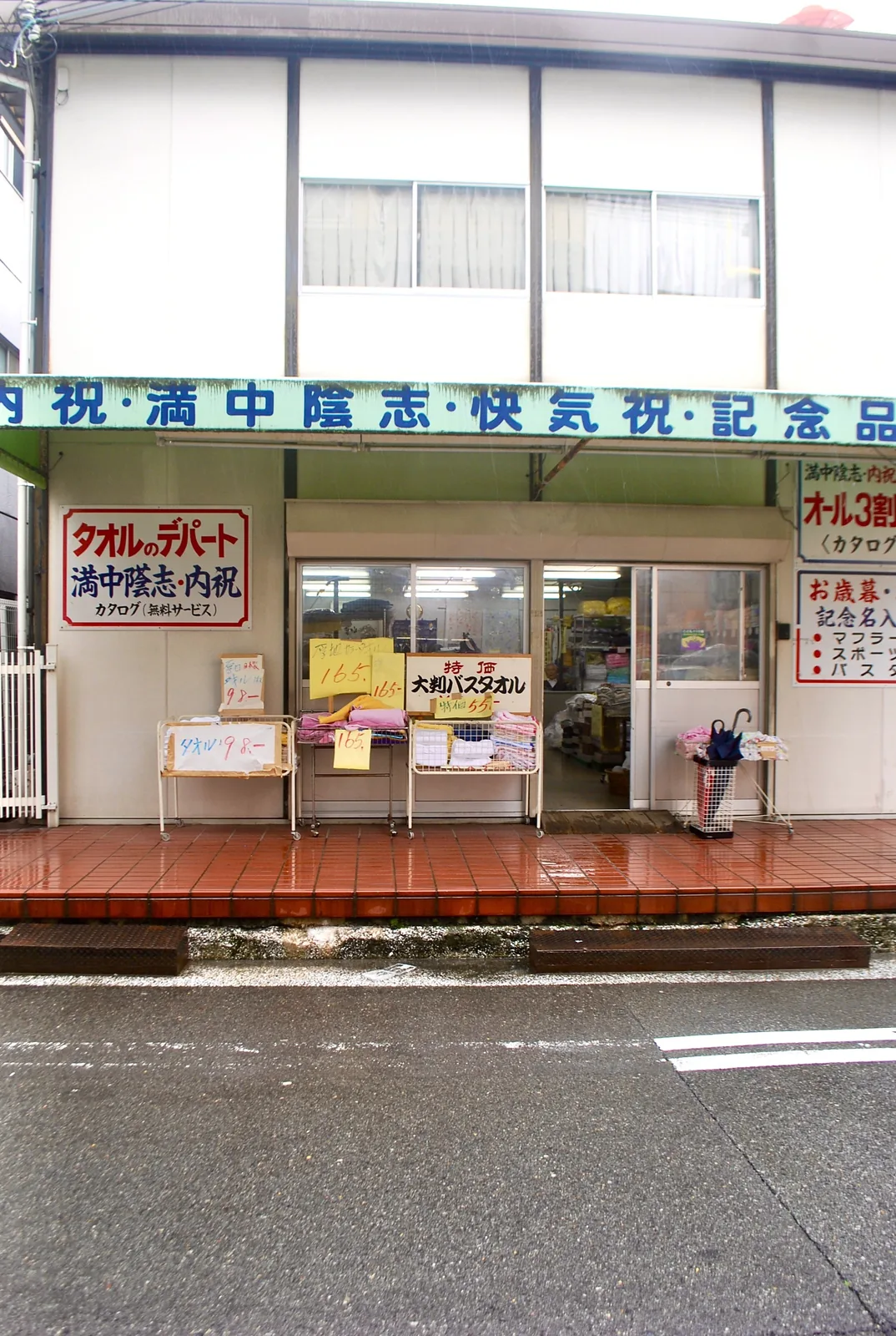 「タオルのデパート」の看板と、タオルが並ぶ店先