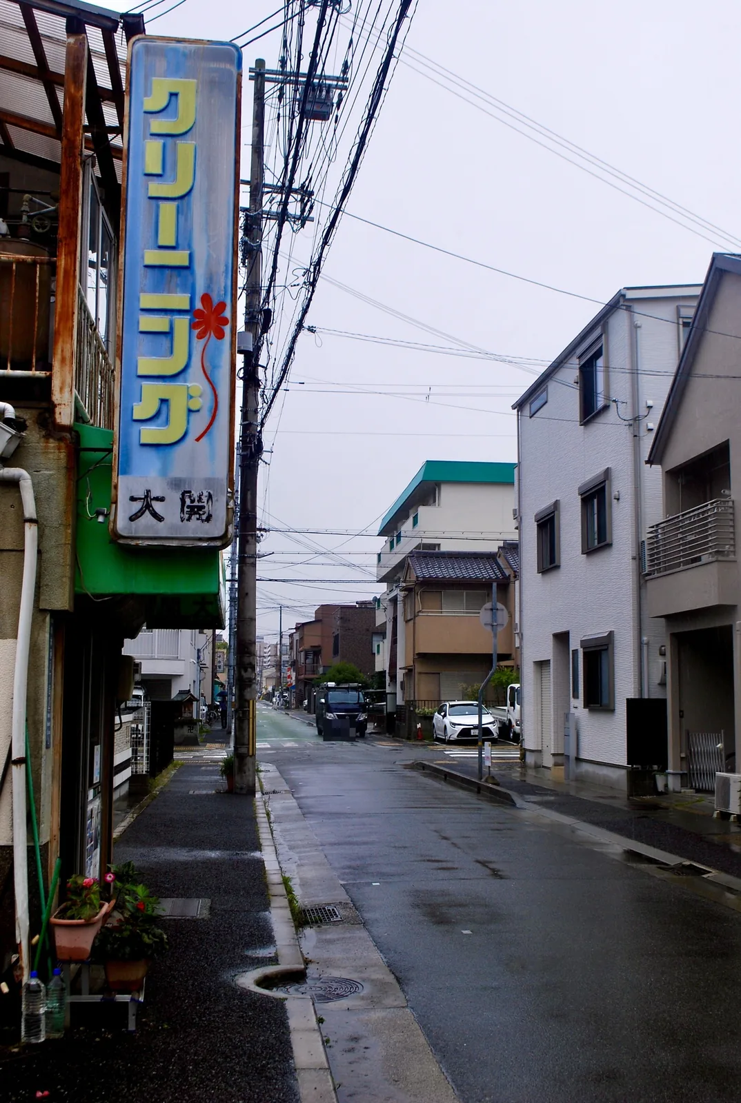 大きなクリーニングの看板の下から、雨の通りを見る風景