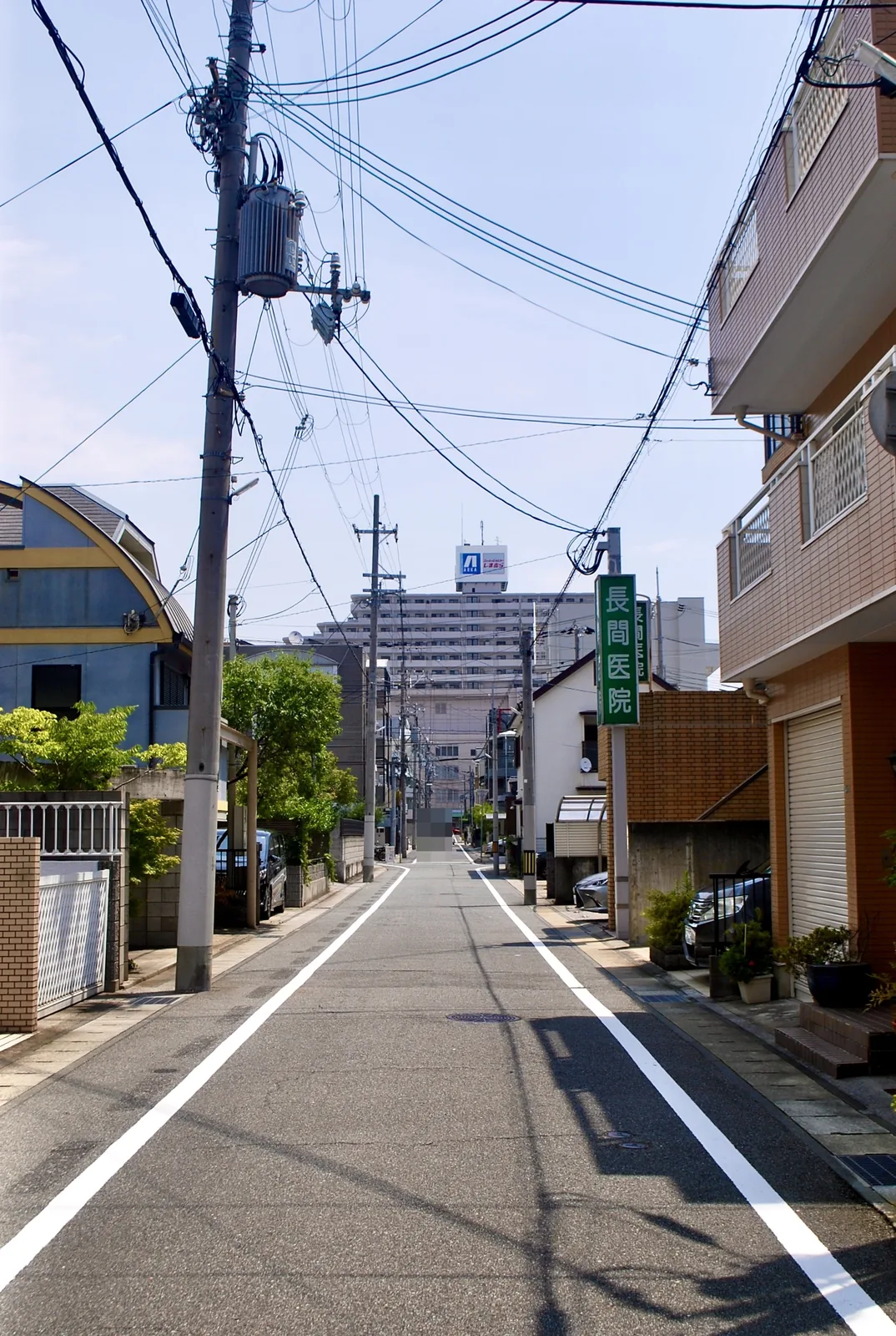 電柱と家々のあいだを、遠くの大きなマンションまでまっすぐ続く道