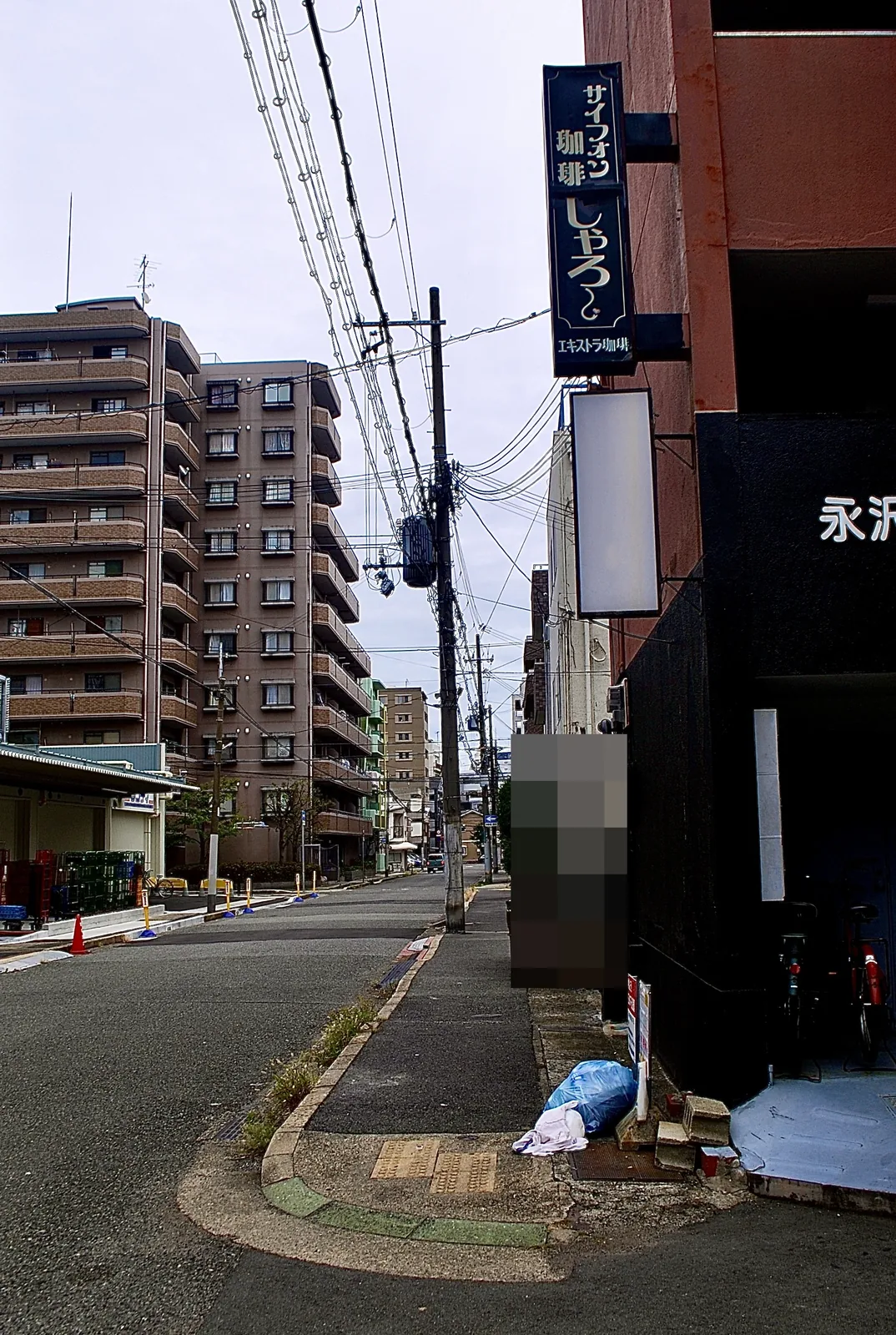 「サイフォン珈琲」の看板の先に、マンションの並ぶまっすぐな道