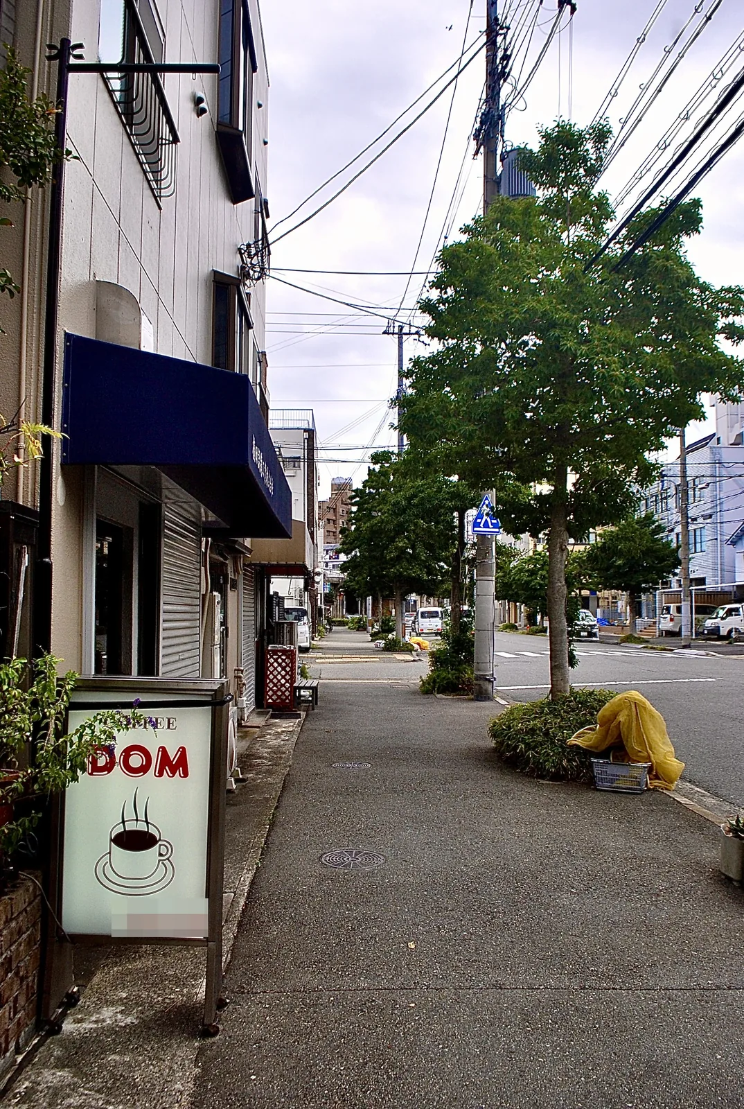 コーヒーカップの絵の「DOM」の看板と、まっすぐな歩道