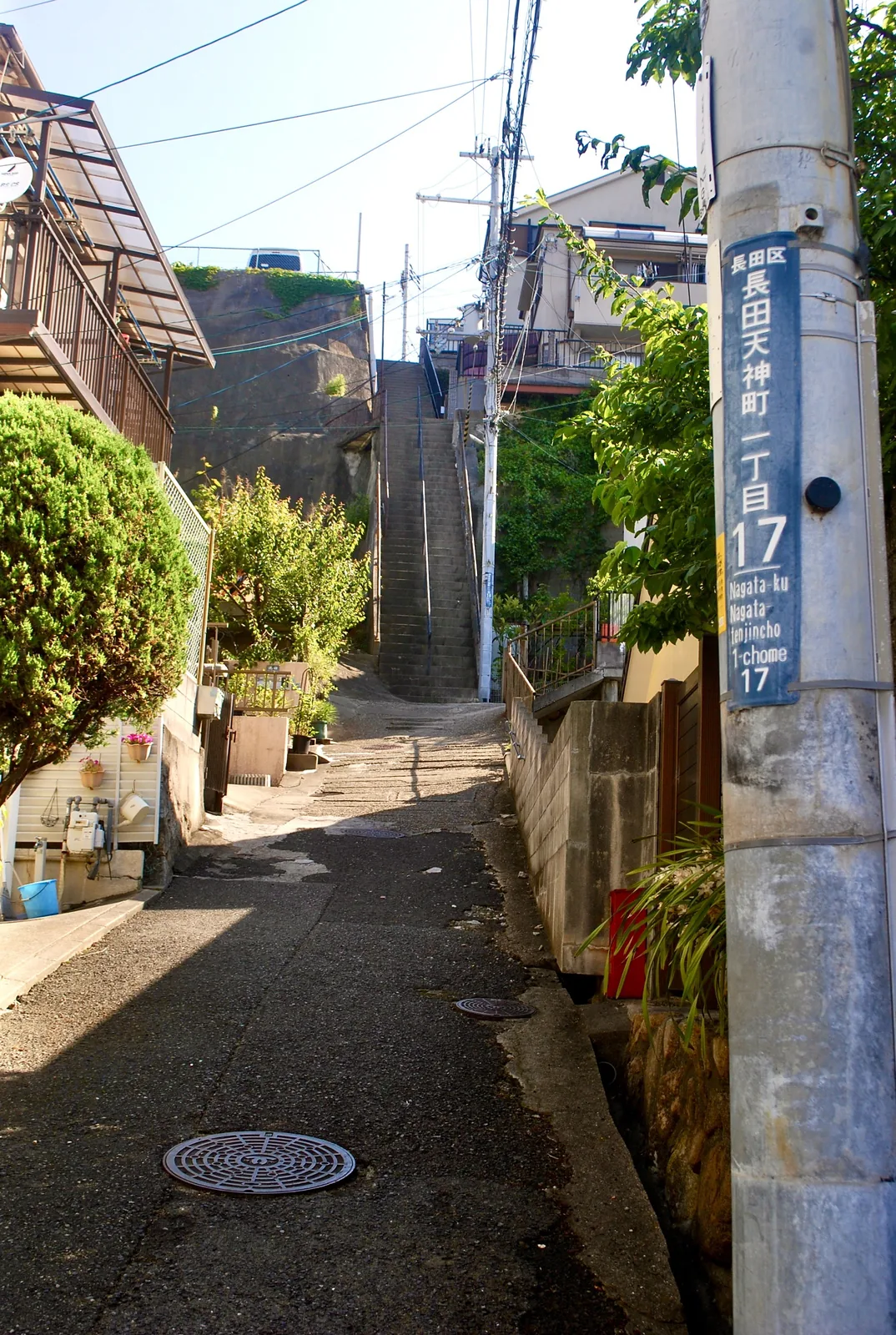 町名表示のある電柱の脇から、奥の石段へ続く路地