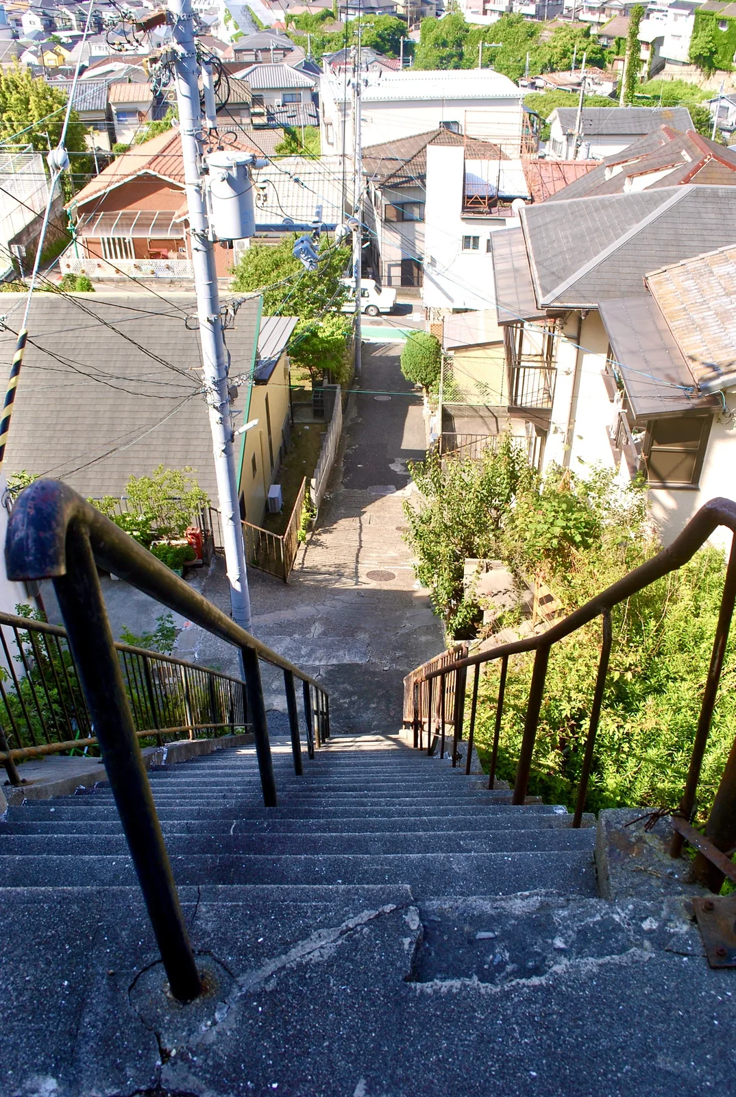 手すりのついた石段の上から、屋根の連なる町を見下ろす風景