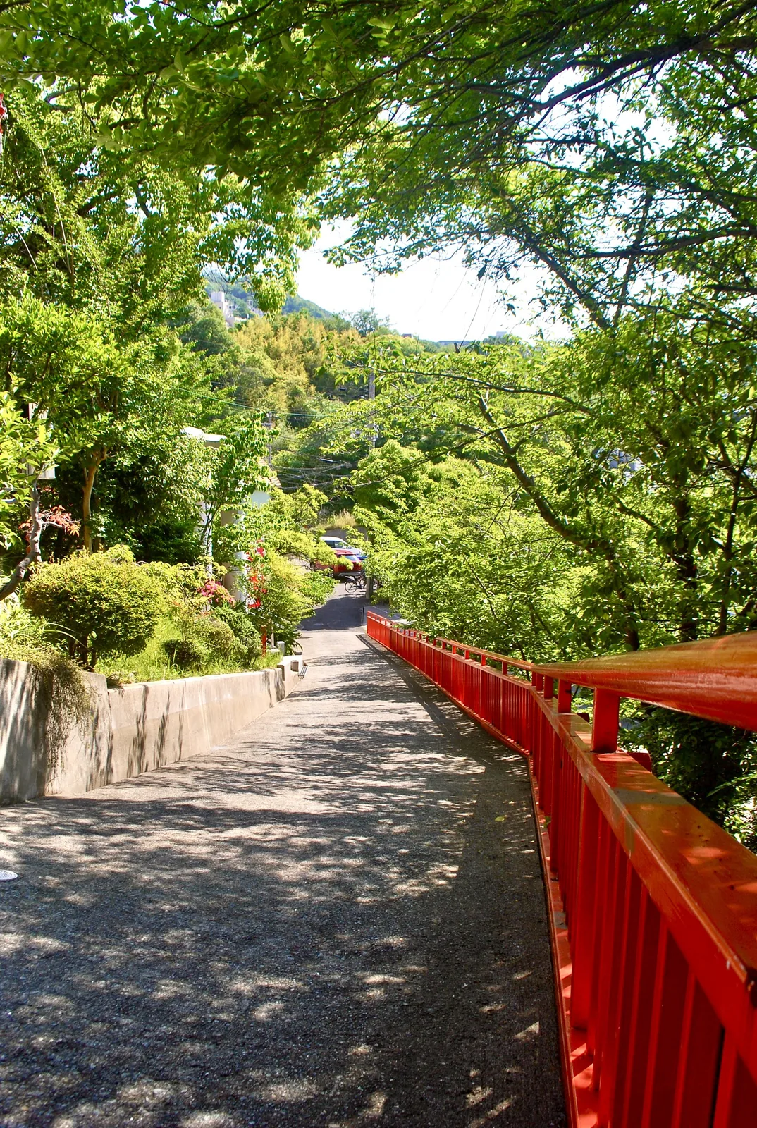 赤い手すりに沿って、木陰の中を続く道