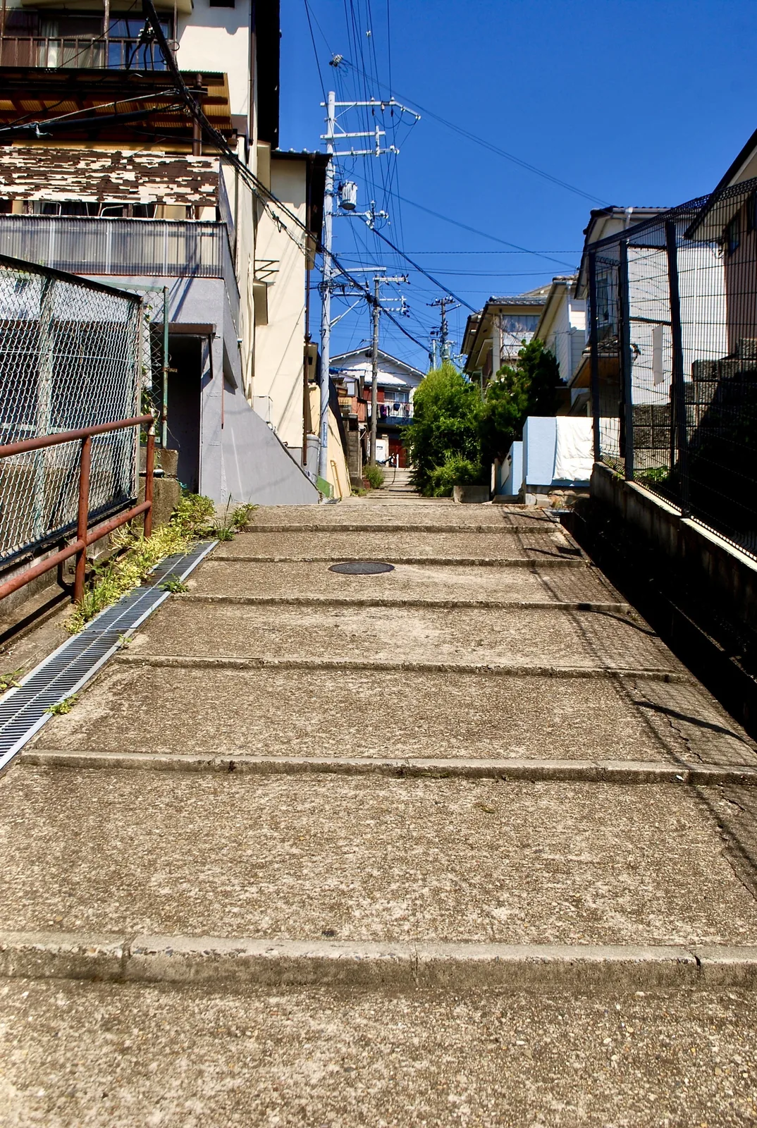 フェンスに沿って、奥へまっすぐ上る広い坂道
