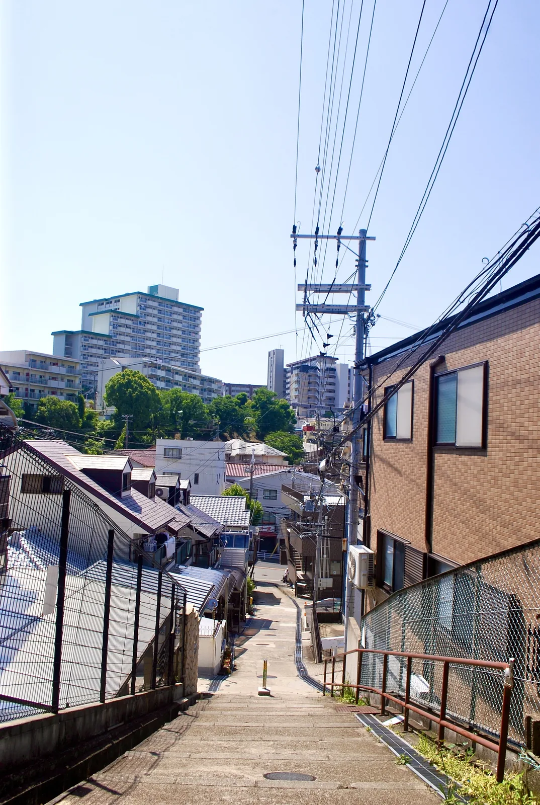 家々の屋根の向こうに、大きな団地がそびえる風景