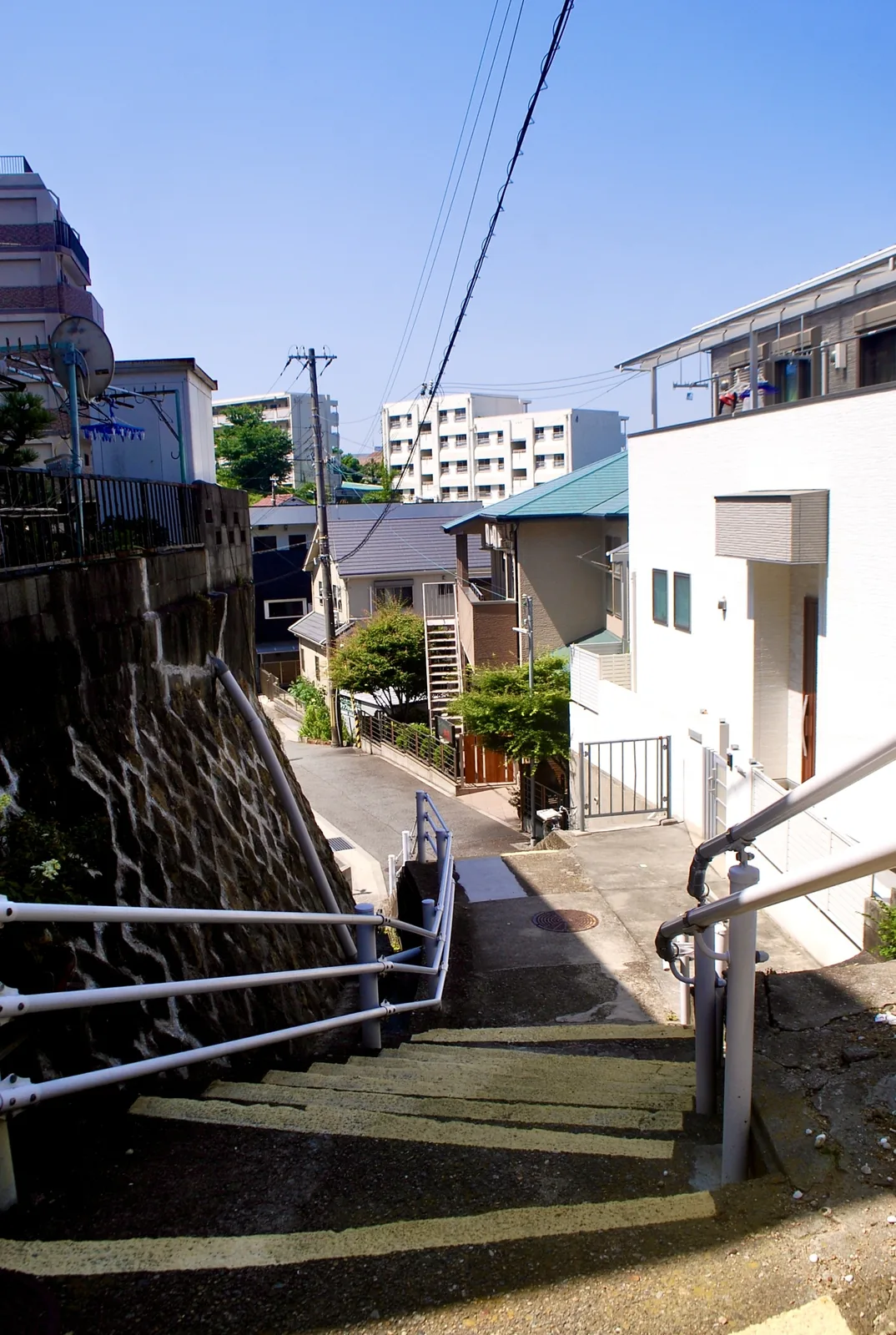 白い手すりのついた、石垣沿いを下る階段