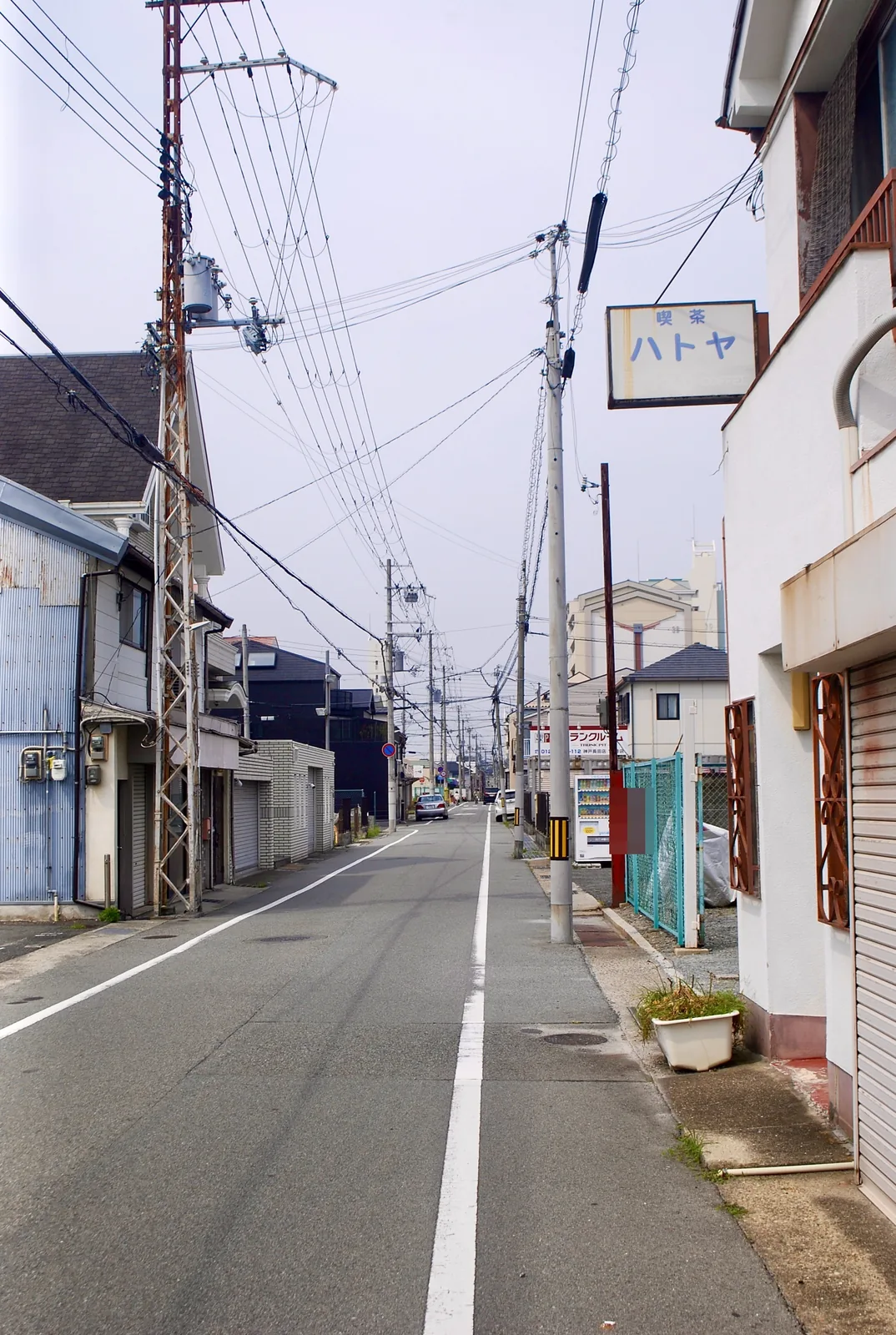 「喫茶 ハトヤ」の看板の先に、電柱がずらりと続くまっすぐな道