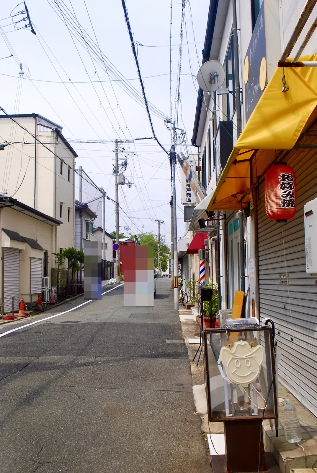 「お好み焼」の赤い提灯とサインポールが並ぶ、まっすぐな通り