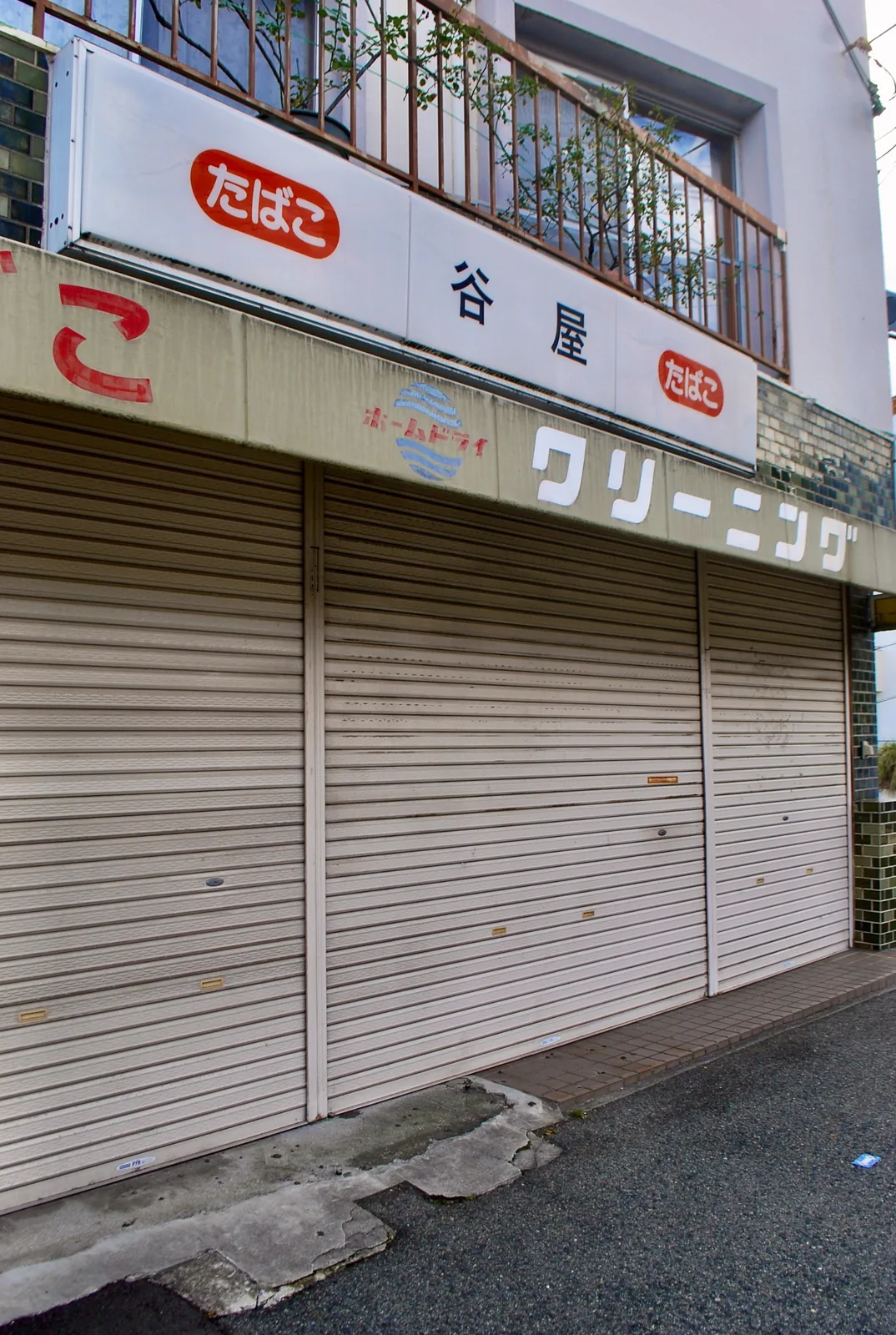 「たばこ」「クリーニング」の色あせた看板と、下りたシャッターを近くから見た店先