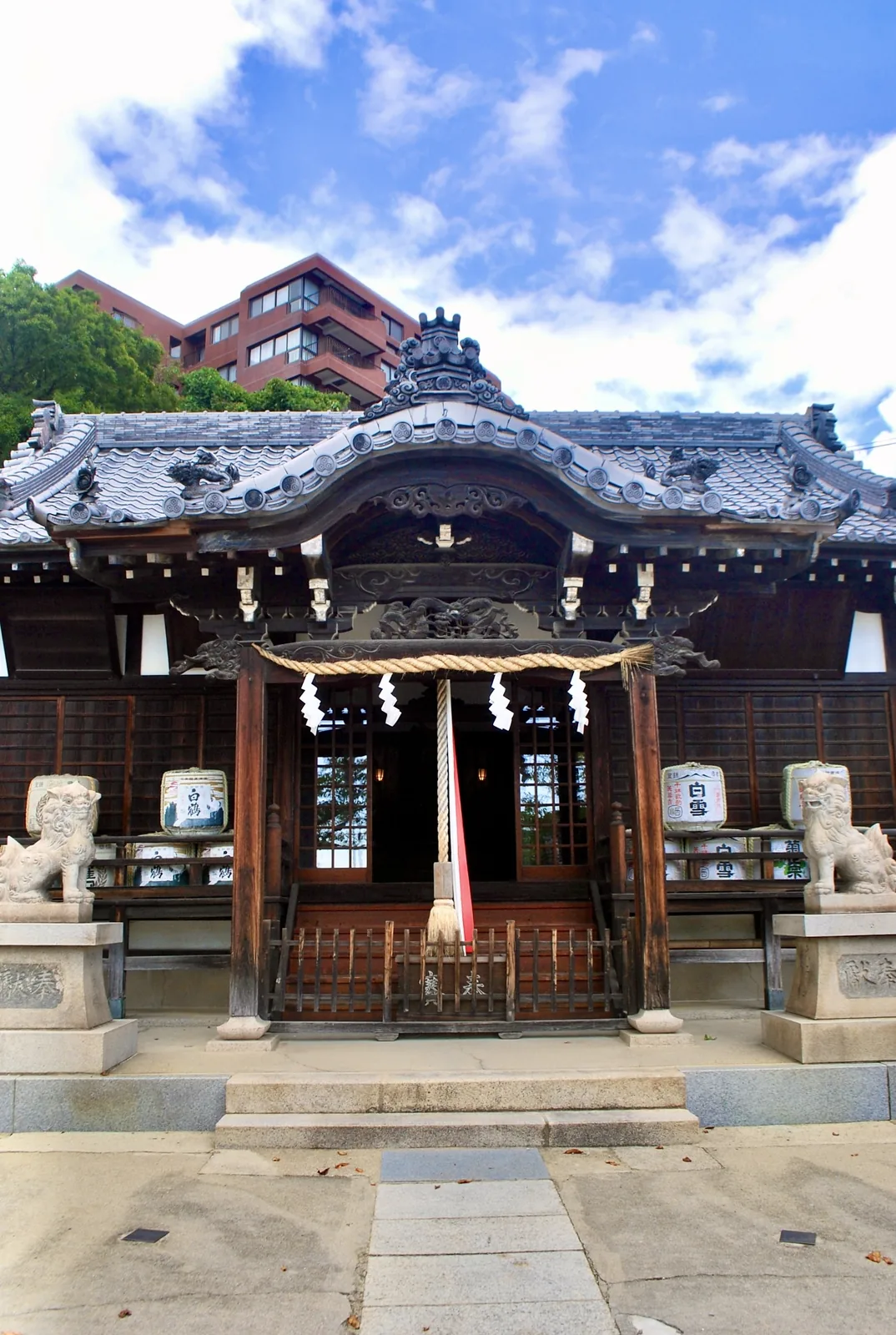 青空と雲を背に、狛犬としめ縄のある神社の拝殿