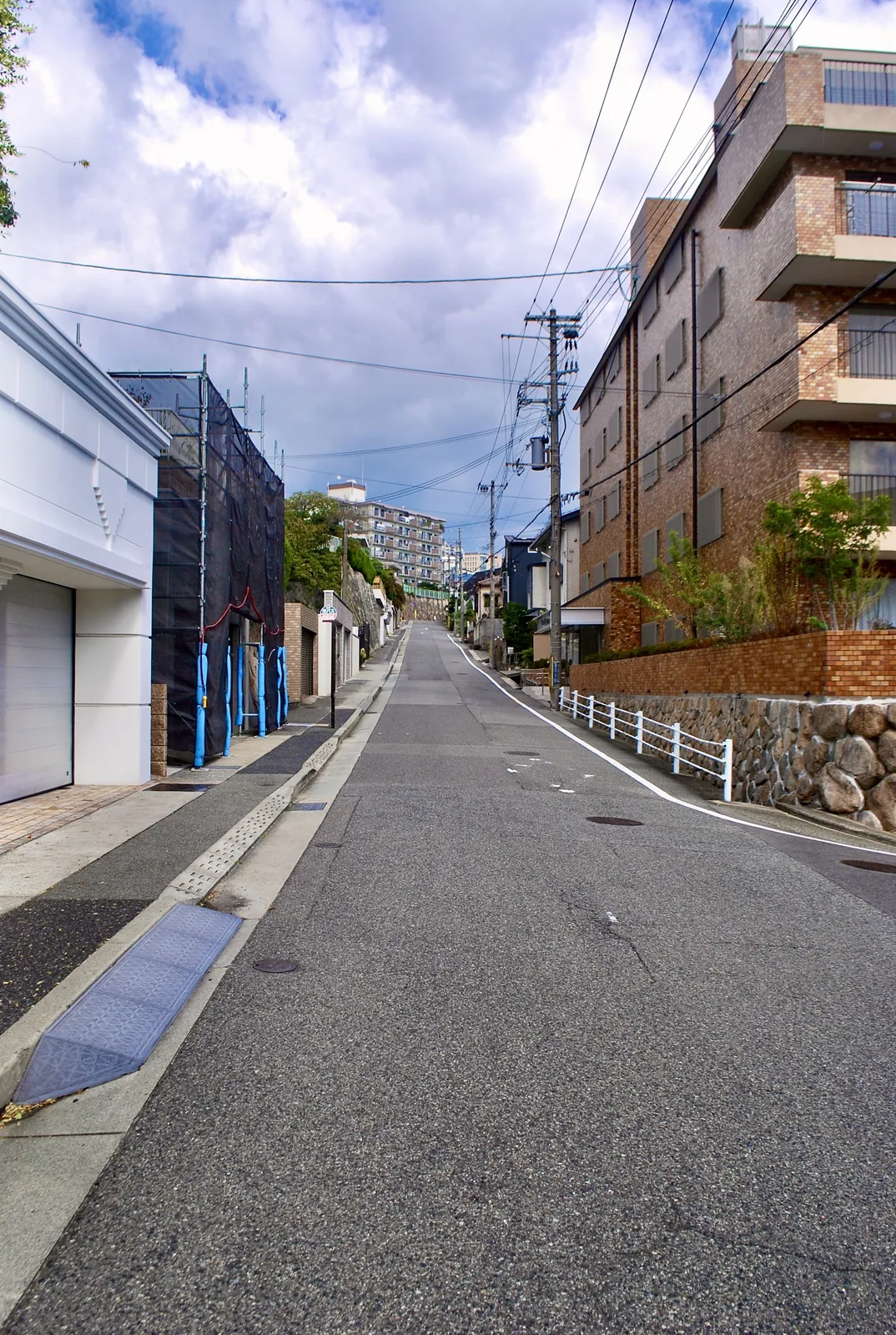 レンガ色のマンションの脇を、奥へまっすぐ上っていく坂道
