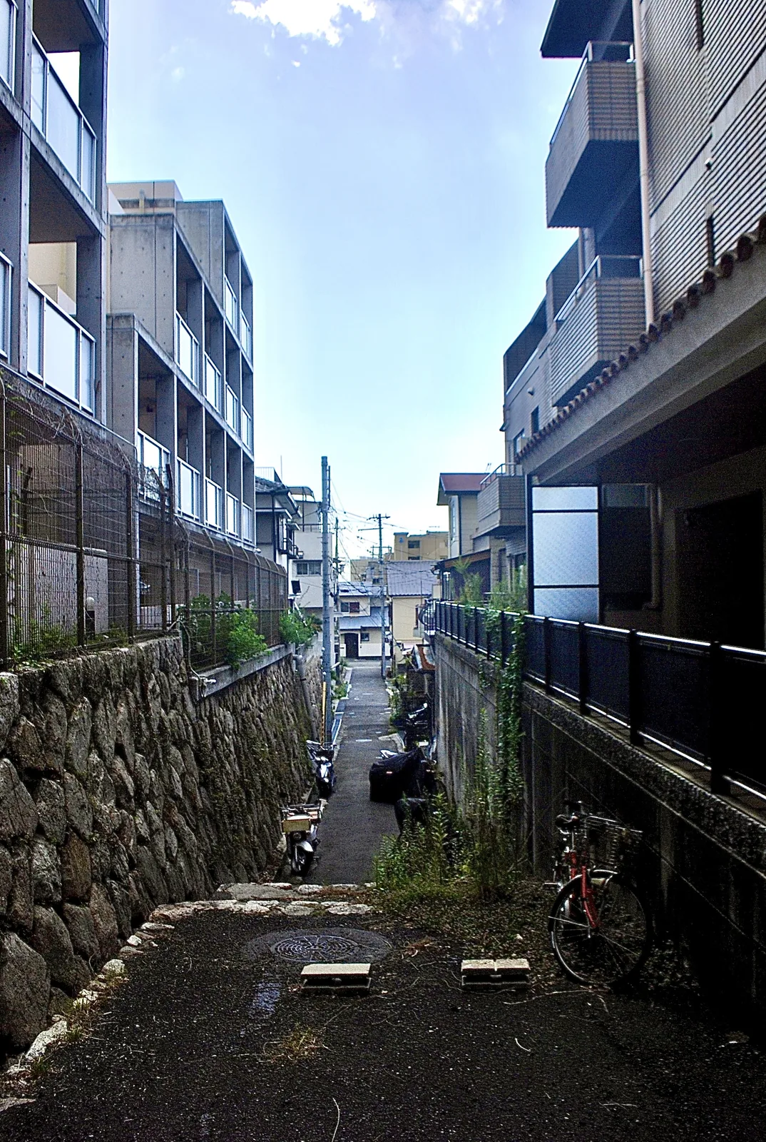 石垣とマンションのあいだを、奥へ細く続く路地