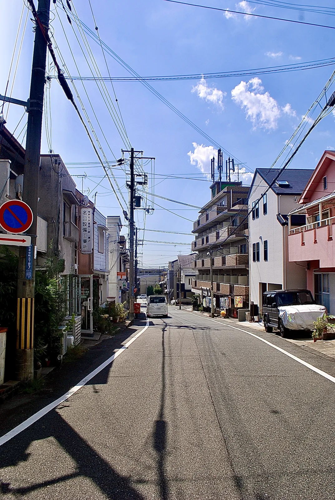 電柱と電線が奥へ続く、青空の下の通り