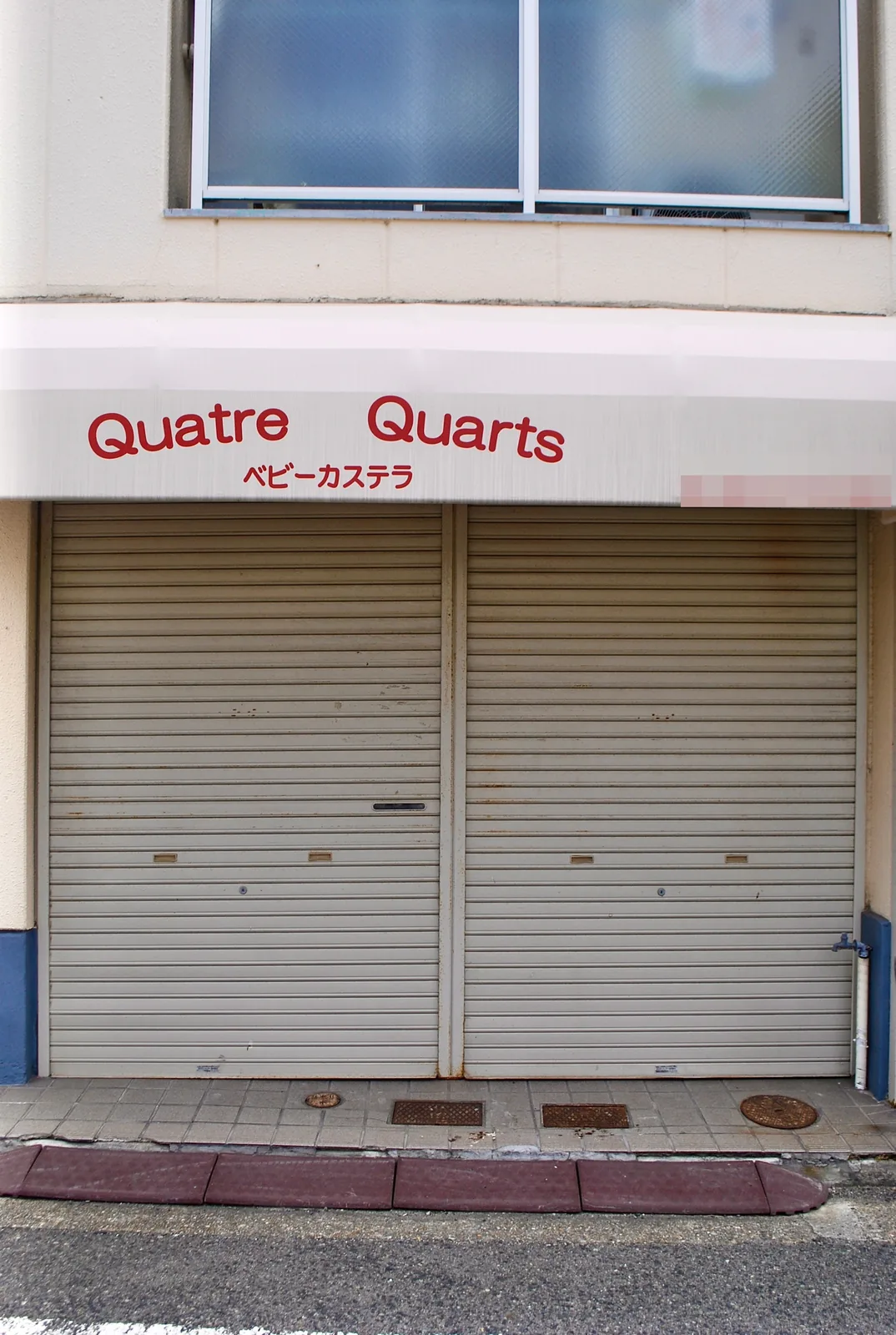 赤い文字の「Quatre Quarts」とシャッターの、ベビーカステラの店