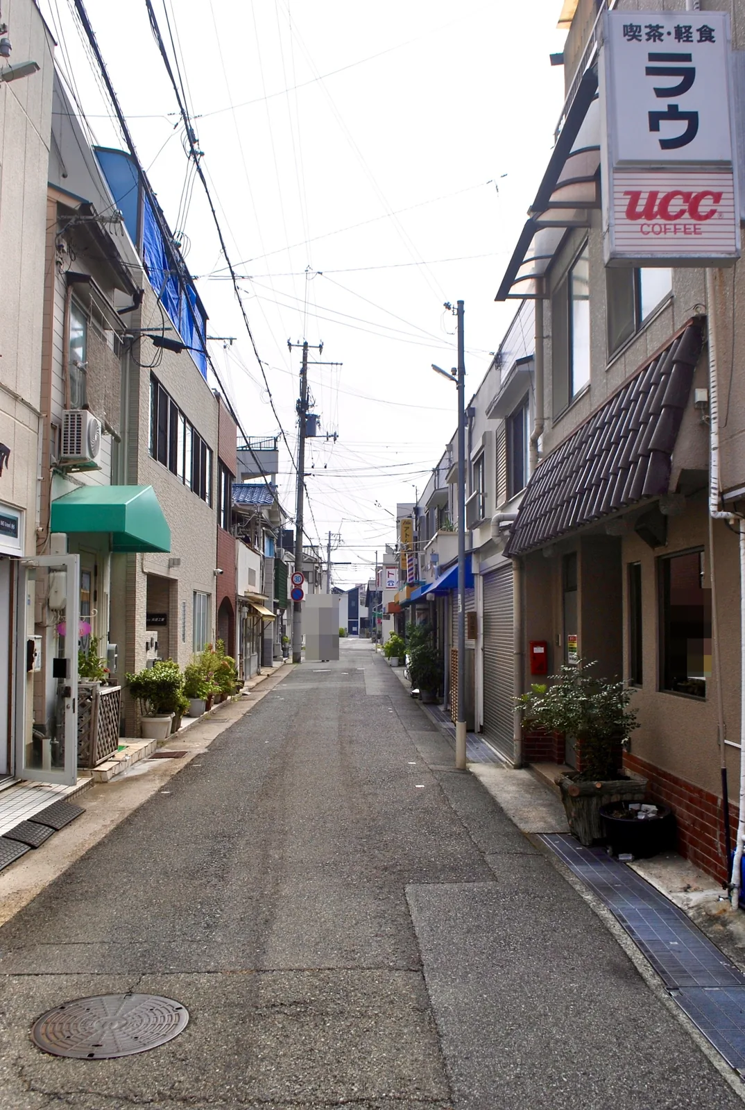 「喫茶・軽食 ラウ」の看板の先に、まっすぐ続く通り