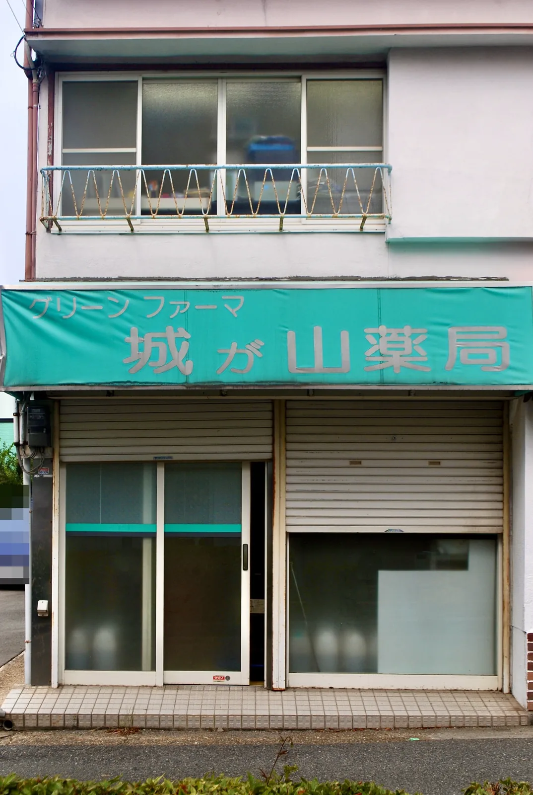 緑の日よけに「城が山薬局」の文字が残る、シャッターの店