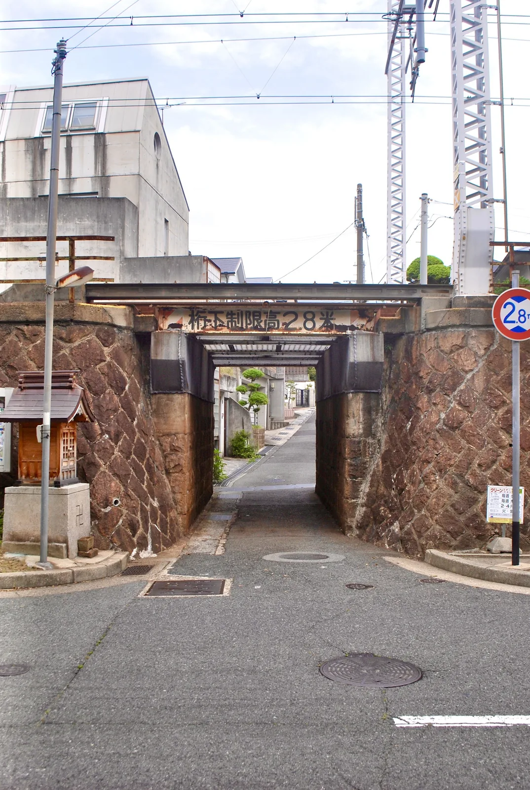 石積みの古いガードの脇に、小さなお社がある風景
