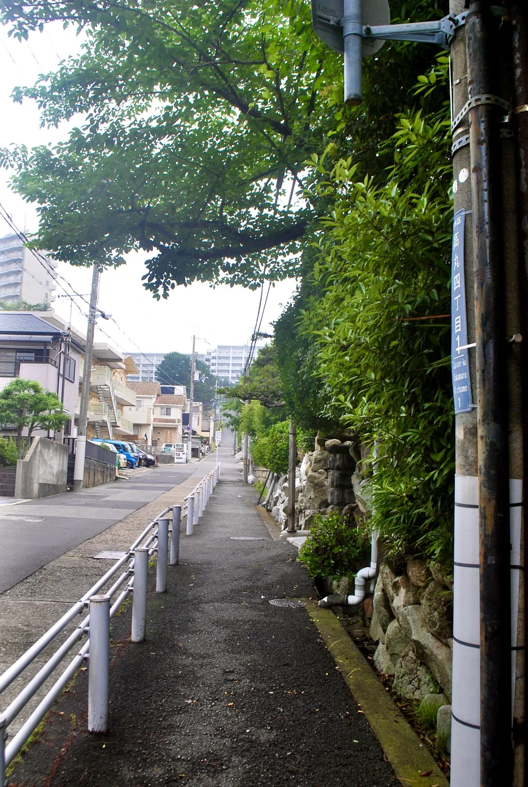 白い手すりに沿って、マンションの見える方へ上る坂道の歩道
